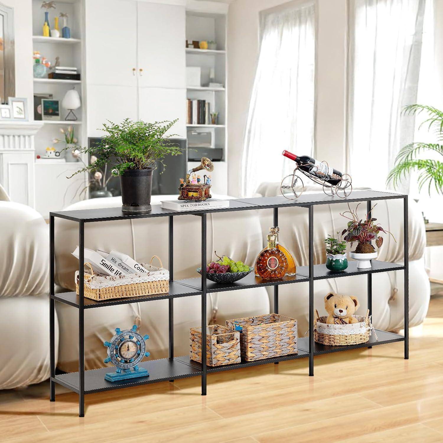 Ein schwarzes Metallkonsolenregal mit Pflanzen, Körben, Deko und einer Spielzeugkanone in einem hellen Wohnzimmer neben einem weißen Sofa.