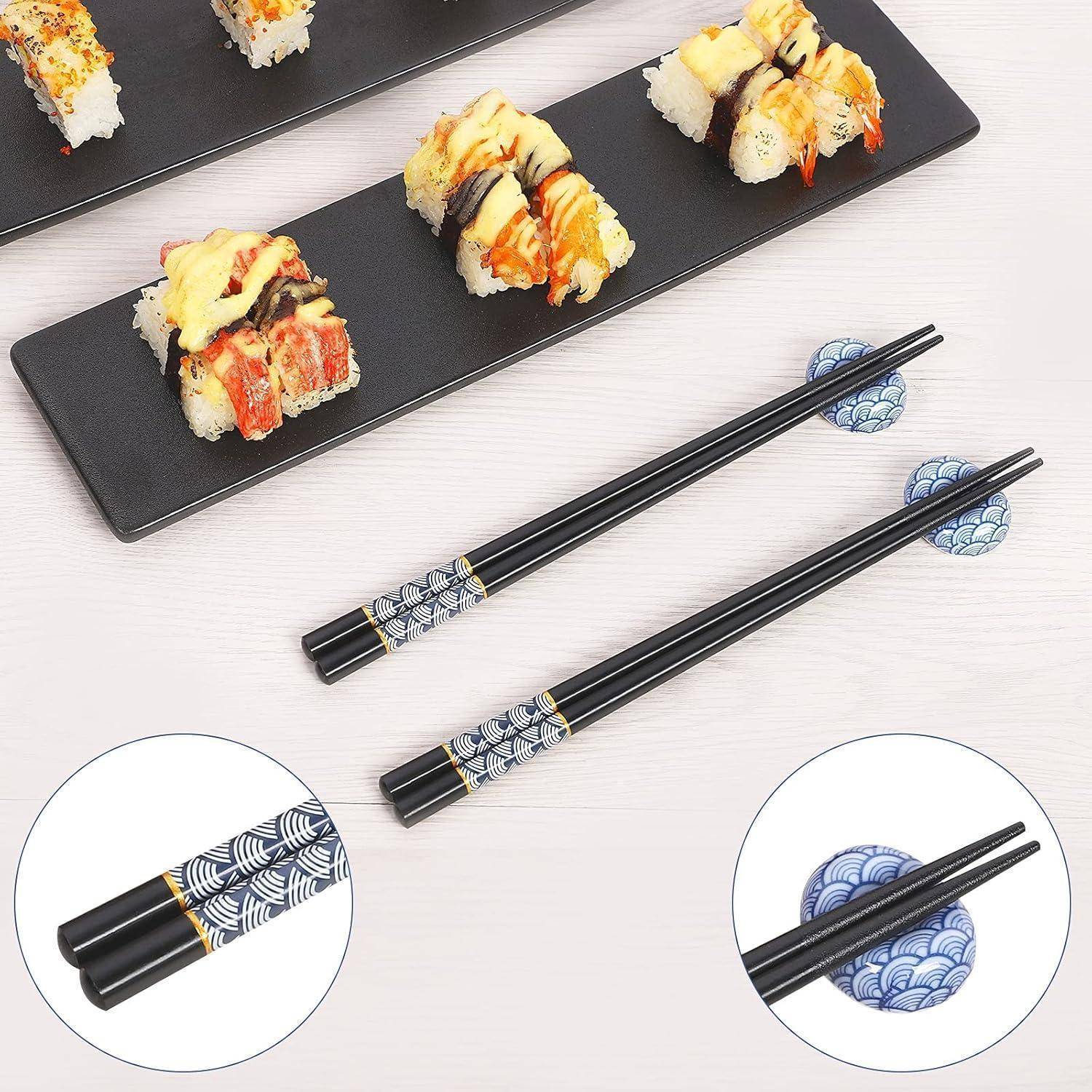Schwarze wiederverwendbare Stäbchen mit blauen gemusterten Ablagen neben Sushi-Rollen auf langen schwarzen Tabletts; eingefügte Nahaufnahmen zeigen die Stäbchenspitzen und dekorativen Griffe.