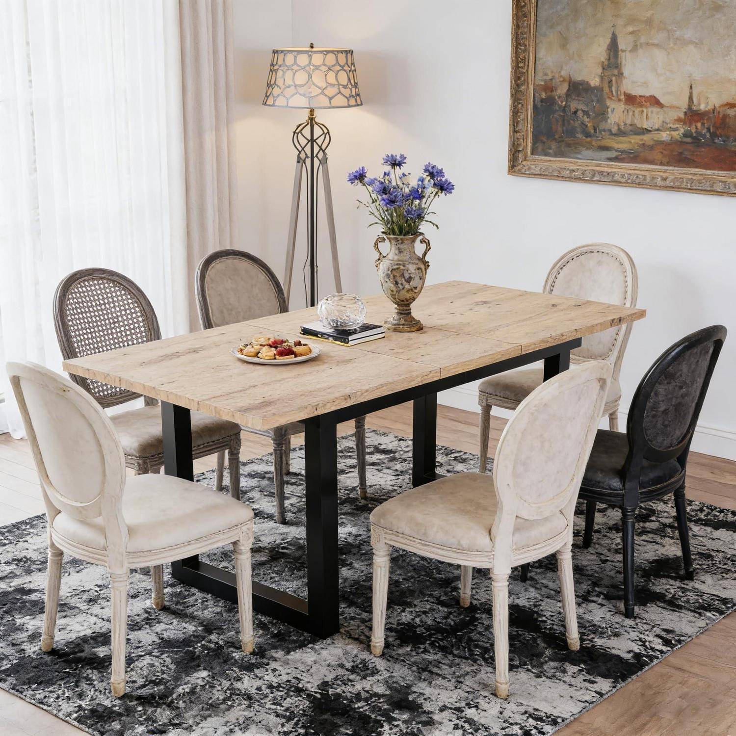 Ein rustikaler Holzesstisch mit sechs gepolsterten Stühlen in einem hellen Esszimmer, dekoriert mit einer Stehleuchte, einer Vase mit Blumen und einem Wandgemälde.
