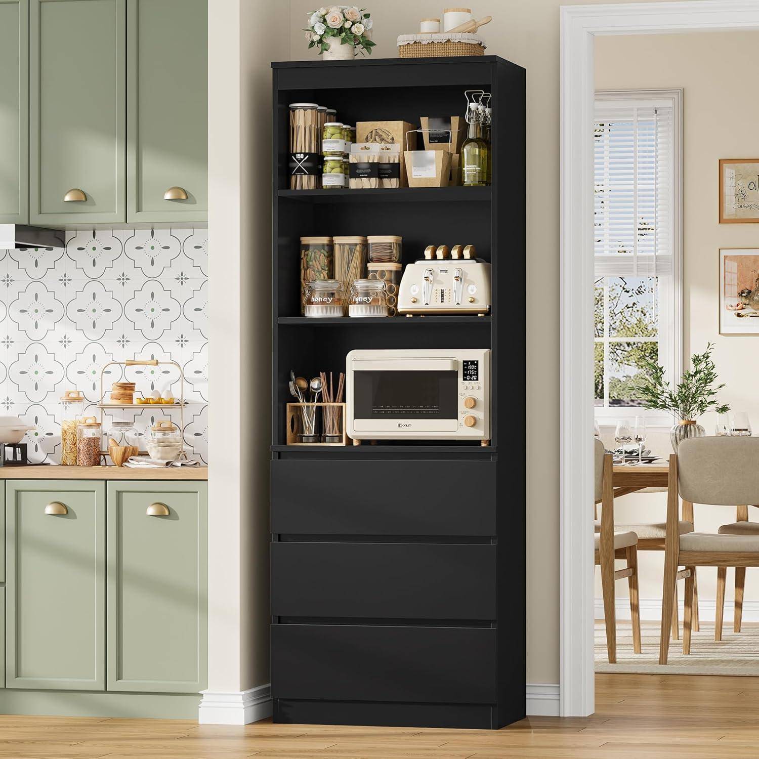 Schwarzer Speisekammerschrank mit offenen Regalen, auf denen Gläser, Körbe und eine Mikrowelle neben einer salbeigrünen Küche und einem Esszimmer stehen.