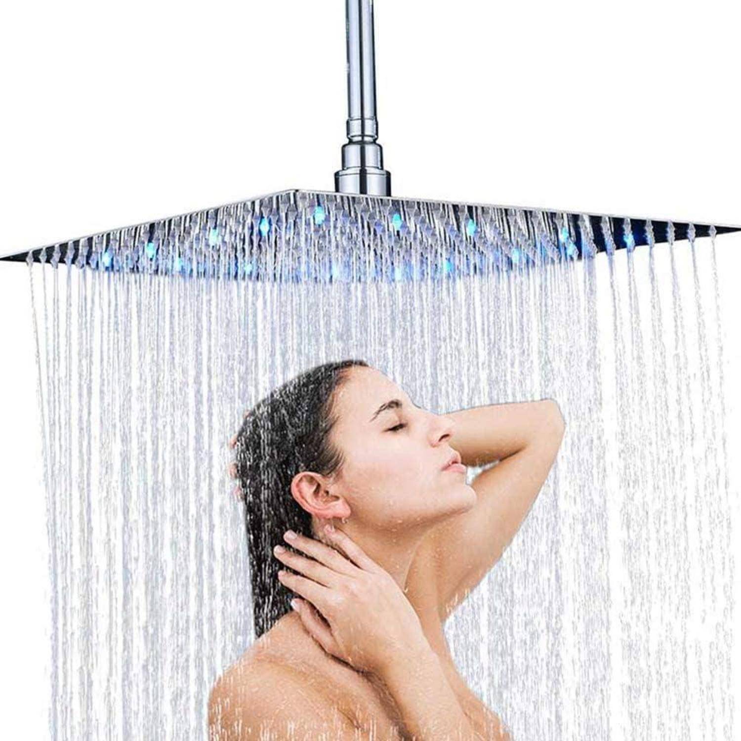 Frau, die unter einer großen quadratischen Regenbrause duscht, mit Wasser, das über ihr Gesicht und ihren Körper fällt.