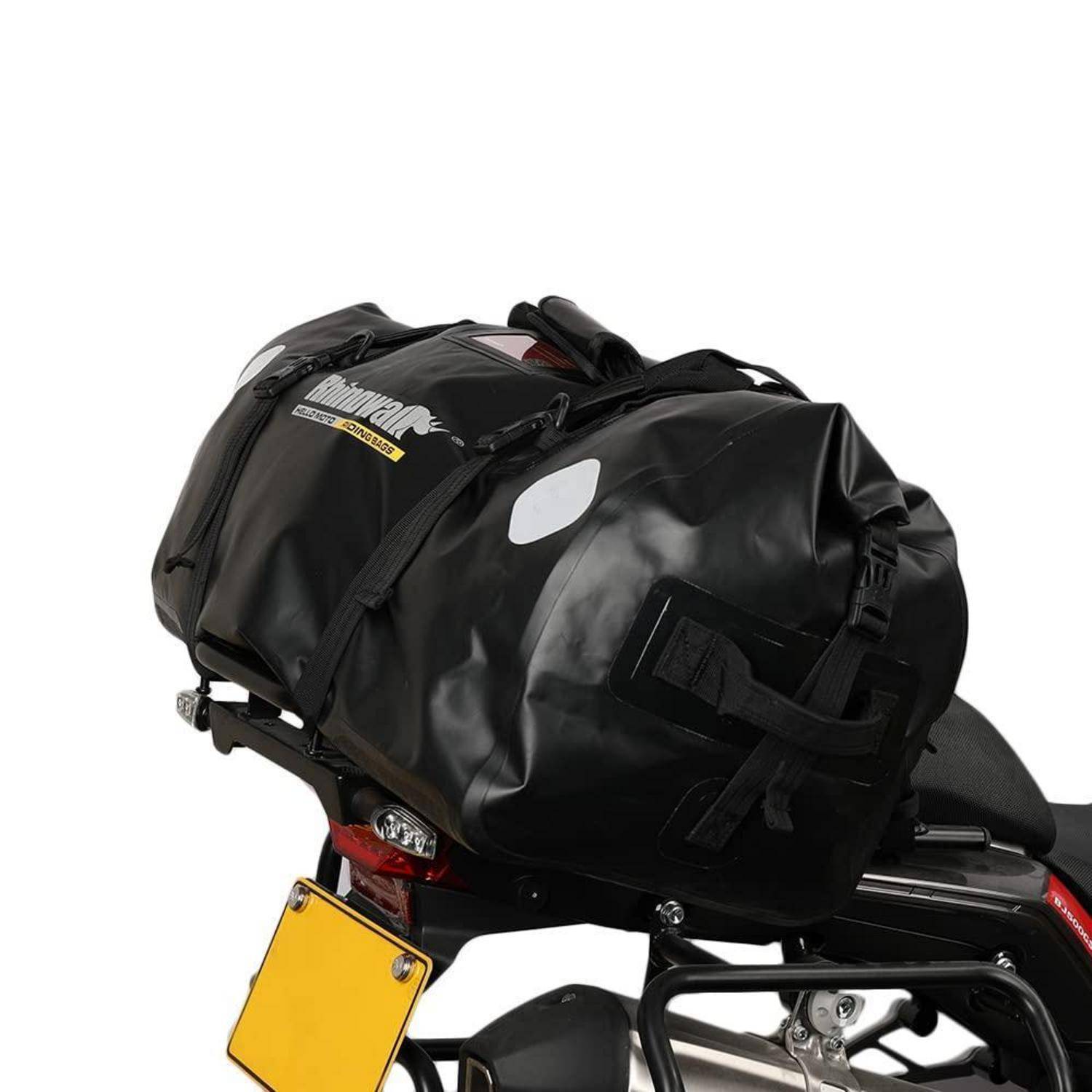 Schwarze Motorradgepäcktasche aus robustem Material, die am hinteren Gepäckträger eines Motorrads befestigt ist, mit reflektierenden Aufnähern und mehreren Tragehenkeln.