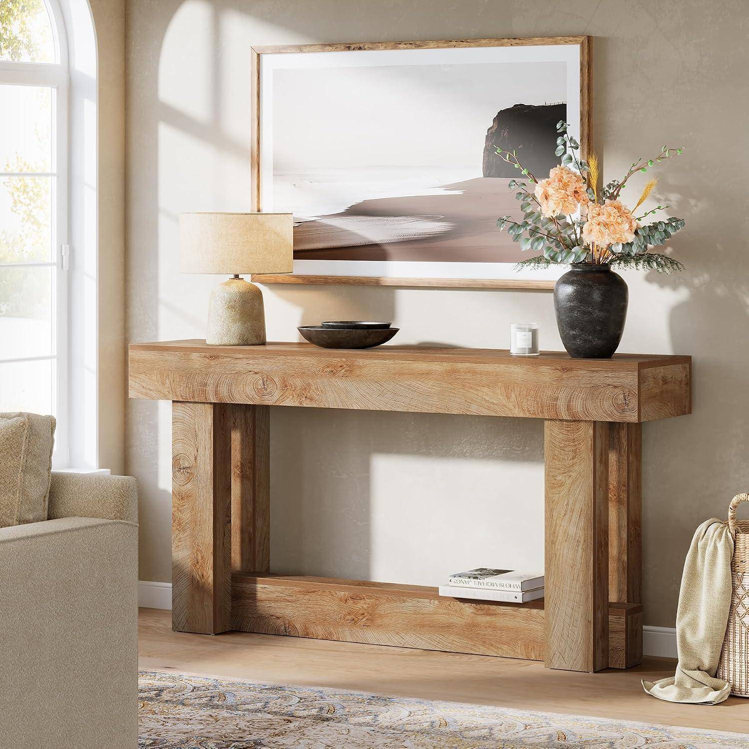 Holzkonsole im Wohnzimmer, stilistisch arrangiert mit Lampe, Schale, Kerze, Blumenvase und gerahmtem Küstenlandschaftsdruck in hellem Licht.