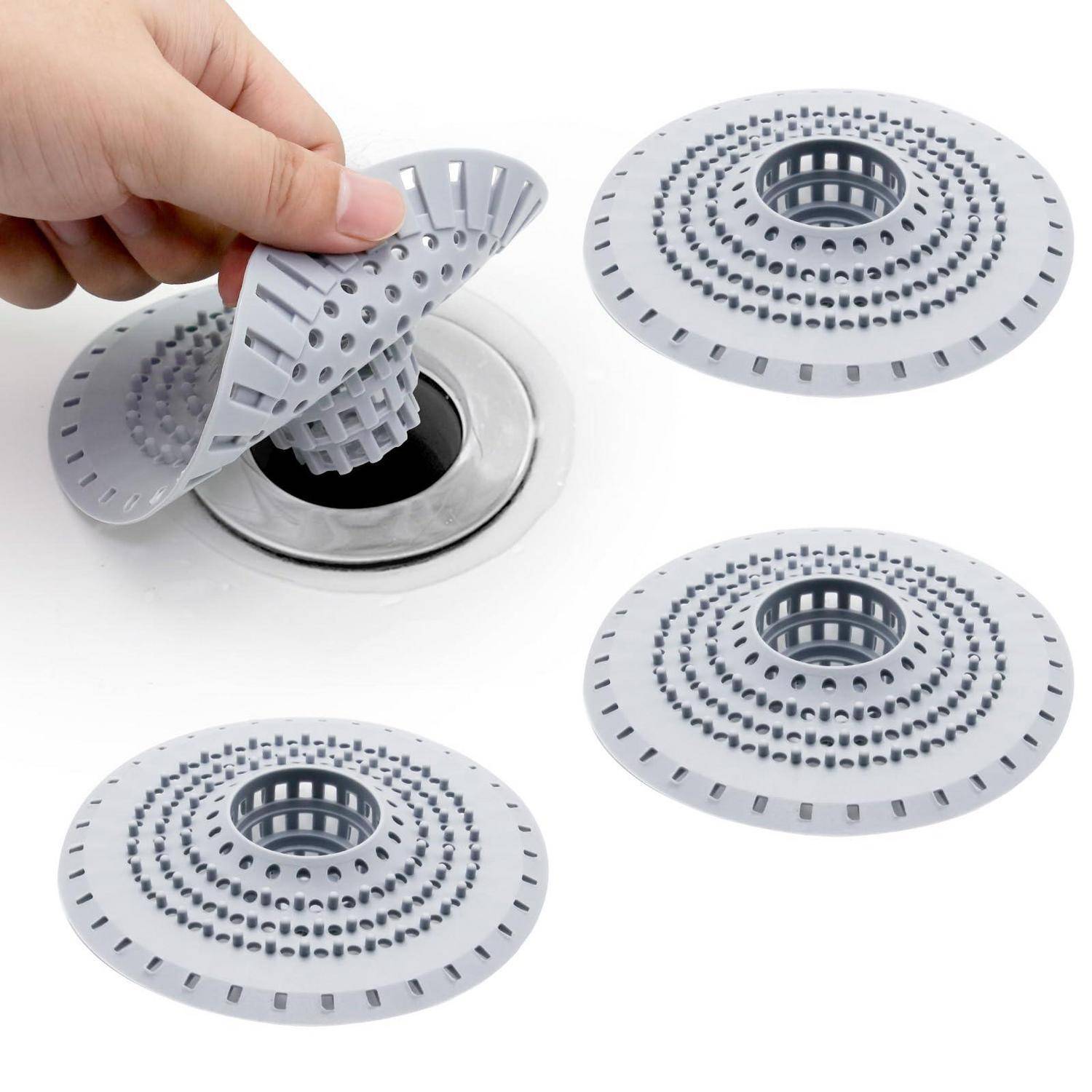 Hand entfernt ein flexibles graues Abflusssieb aus einem Spülbecken; drei passende kreisförmige Siebe werden als Produkt mit ihrem perforierten Design gezeigt.