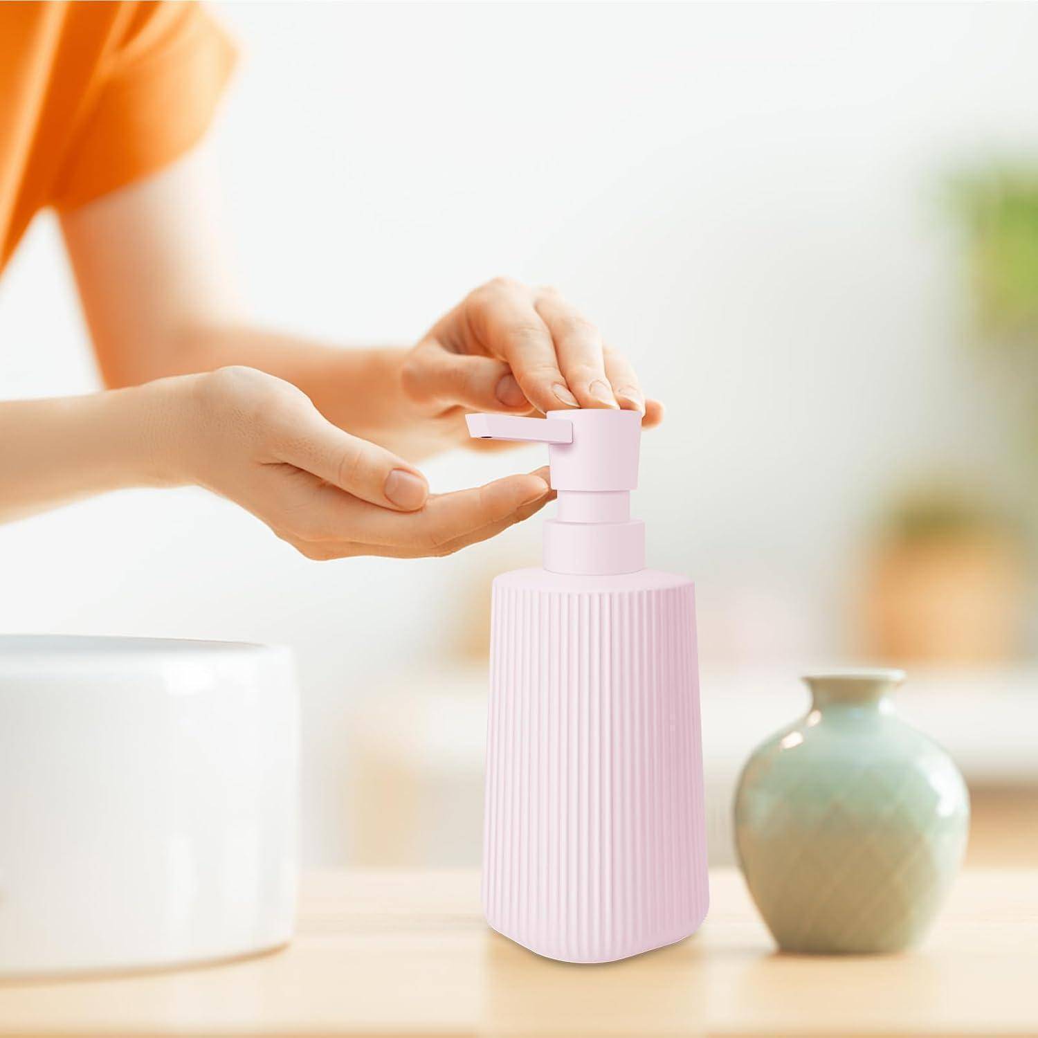 Person, die Seife aus einer rosa Pumpflasche neben einem Waschbecken ausgießt, mit einer kleinen Vase im Hintergrund.