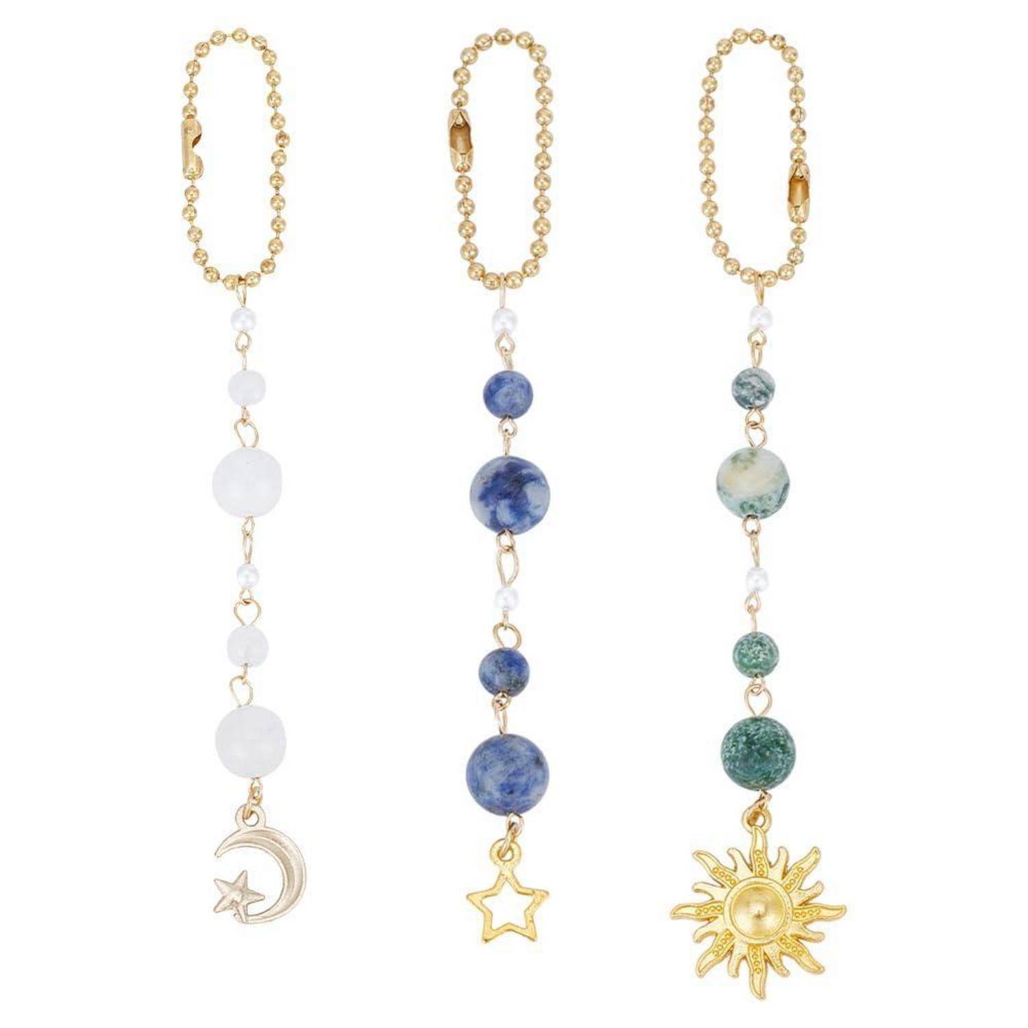 Drei Perlen-Charm-Halsketten auf weißem Hintergrund: weiße Perlen mit Halbmond und Stern, blaue Perlen mit Stern und grünblaue Perlen mit Sonne.