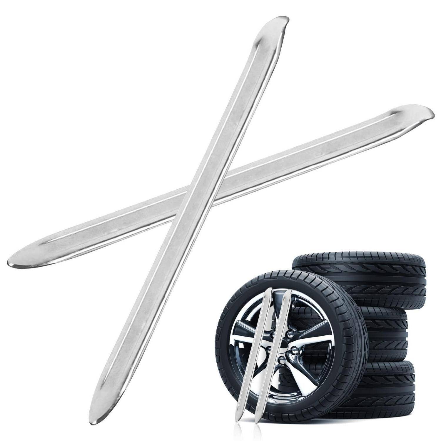 Gekreuzte Metallreifeneisen über einem Stapel von Autoreifen und einem Rad, was auf einen Reifenwechsel oder eine Reparatur hindeutet.