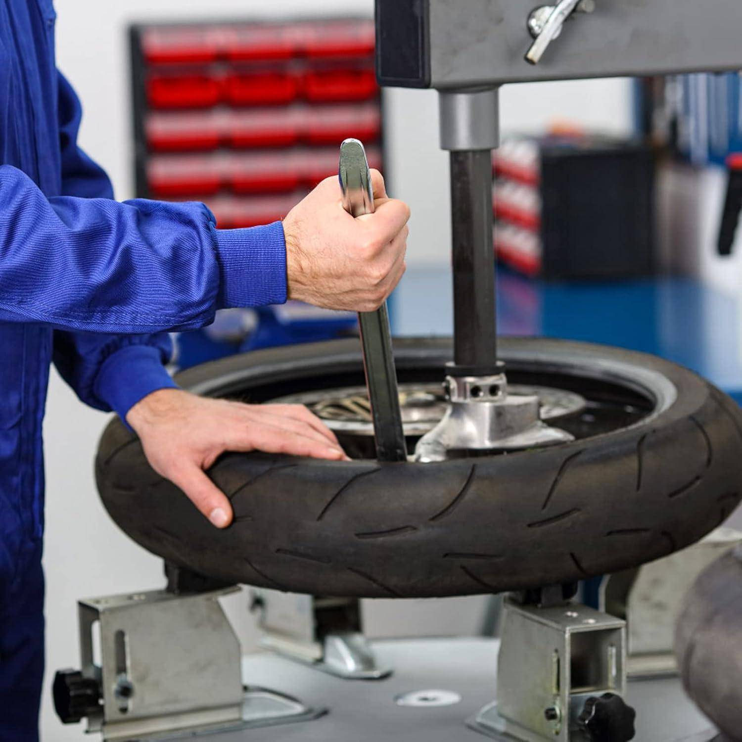 Mechaniker, der eine Reifenwechselmaschine verwendet, um einen Motorradreifen von der Felge zu entfernen.