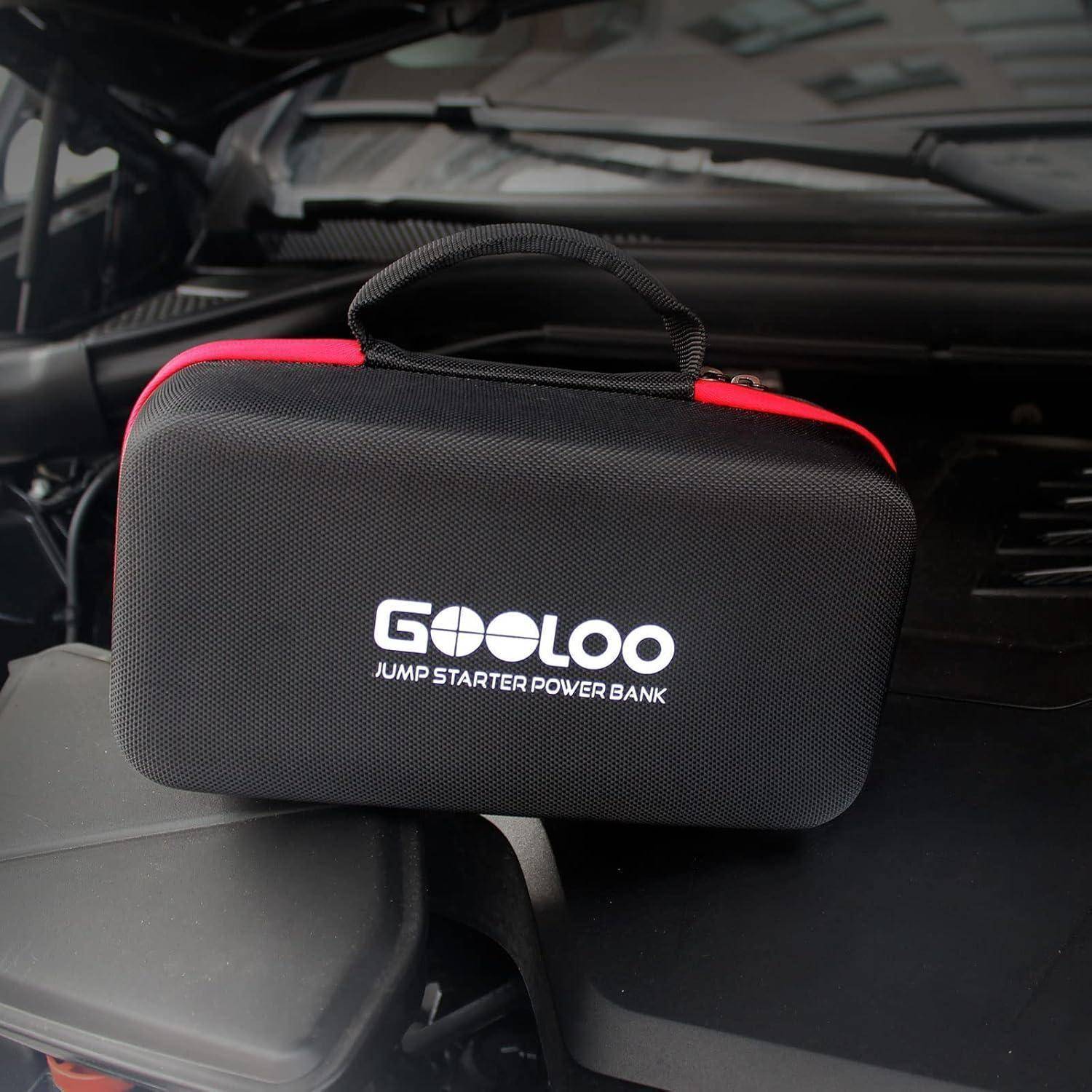 Eine GOOLOO Starthilfegerät-Powerbank liegt im Motorraum eines Autos und zeigt das Markenlogo und den Griff auf einer schwarzen Tasche mit Reißverschluss.