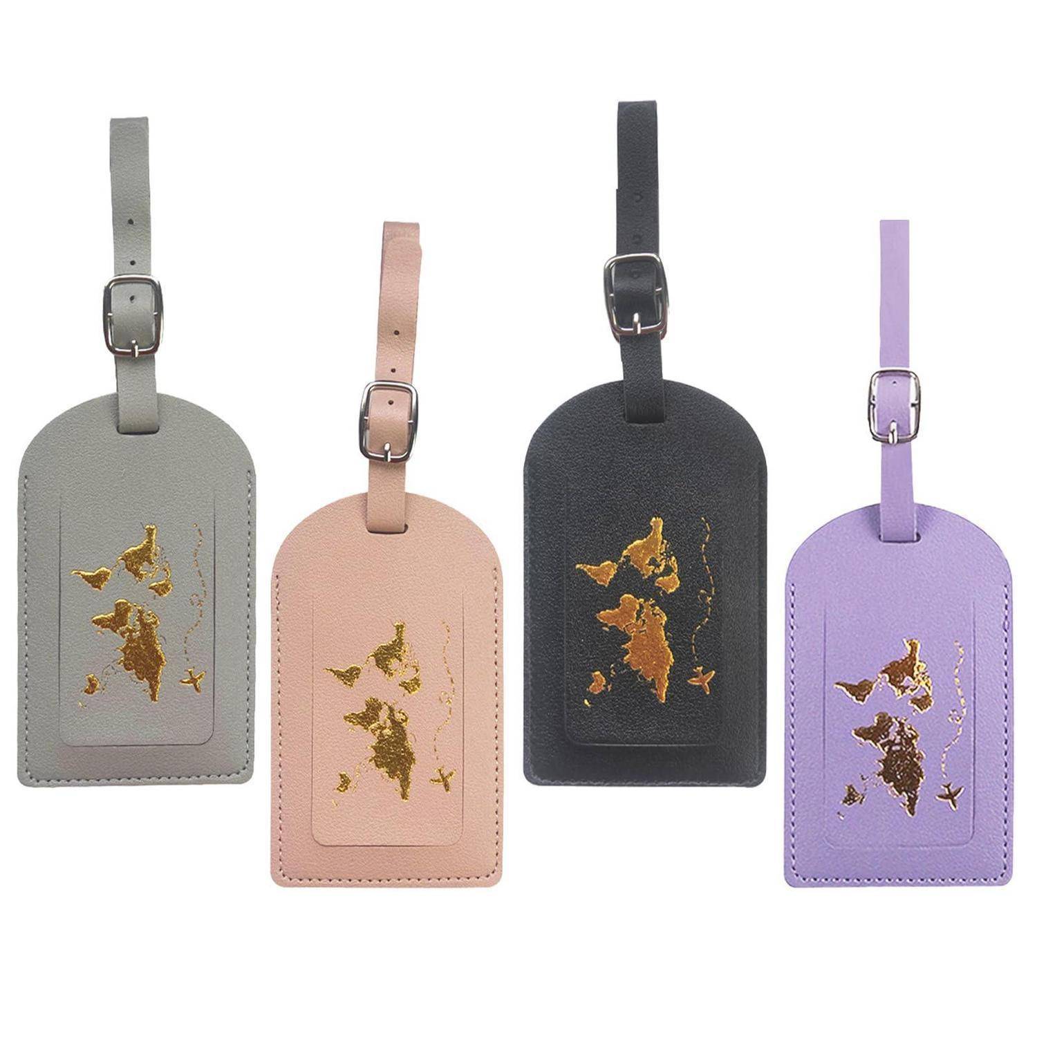 Vier Lederreiseetiketten in Grau, Rosa, Schwarz und Lavendel, jeweils mit einem goldenen kartenähnlichen Design und Schnallengurt.