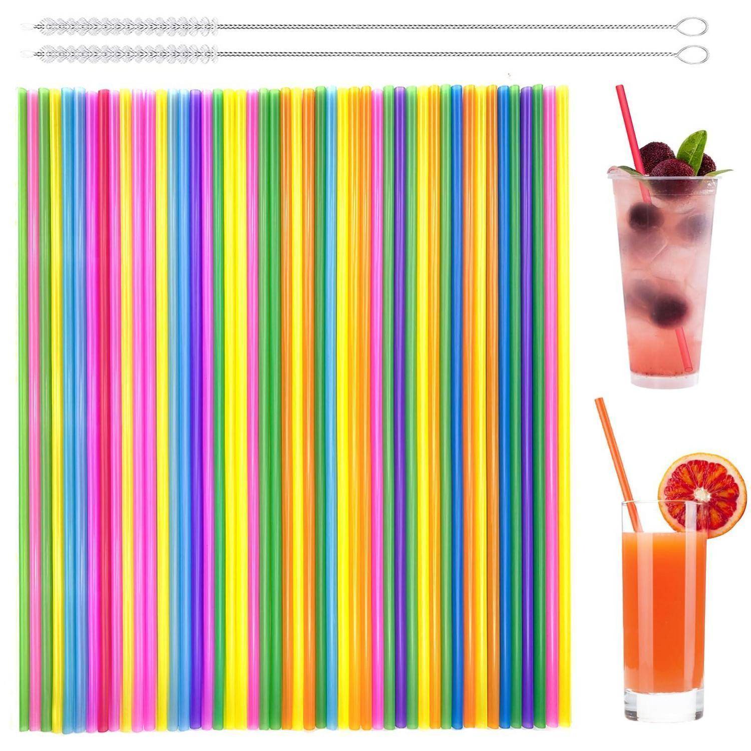 Bunte gestreifte Kunststoff-Trinkhalme, die in einem Block angeordnet sind, mit zwei klaren Cocktailgläsern mit rosa und orangefarbenen Getränken auf der rechten Seite.