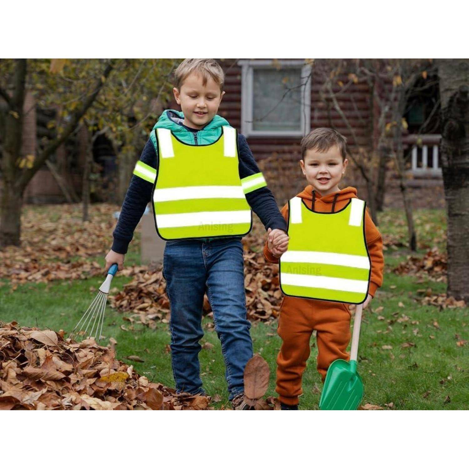 Zwei Kinder in reflektierenden Sicherheitswesten helfen dabei, Blätter im Garten zu rechen, halten sich draußen an den Händen in der Nähe eines Hauses.