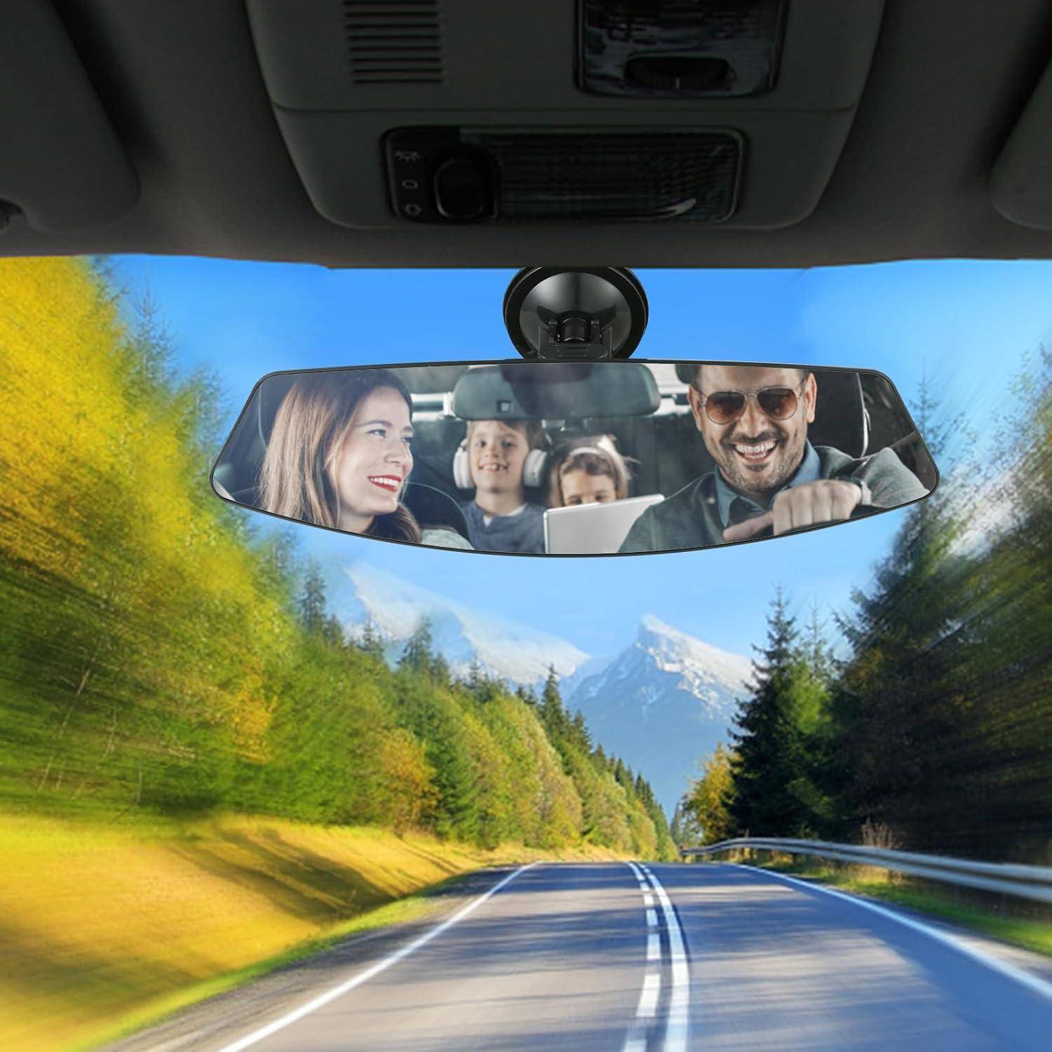 Familie fährt auf einer malerischen Bergstraße, von innen aus dem Auto fotografiert mit Eltern und Kindern, die sich im Rückspiegel spiegeln.