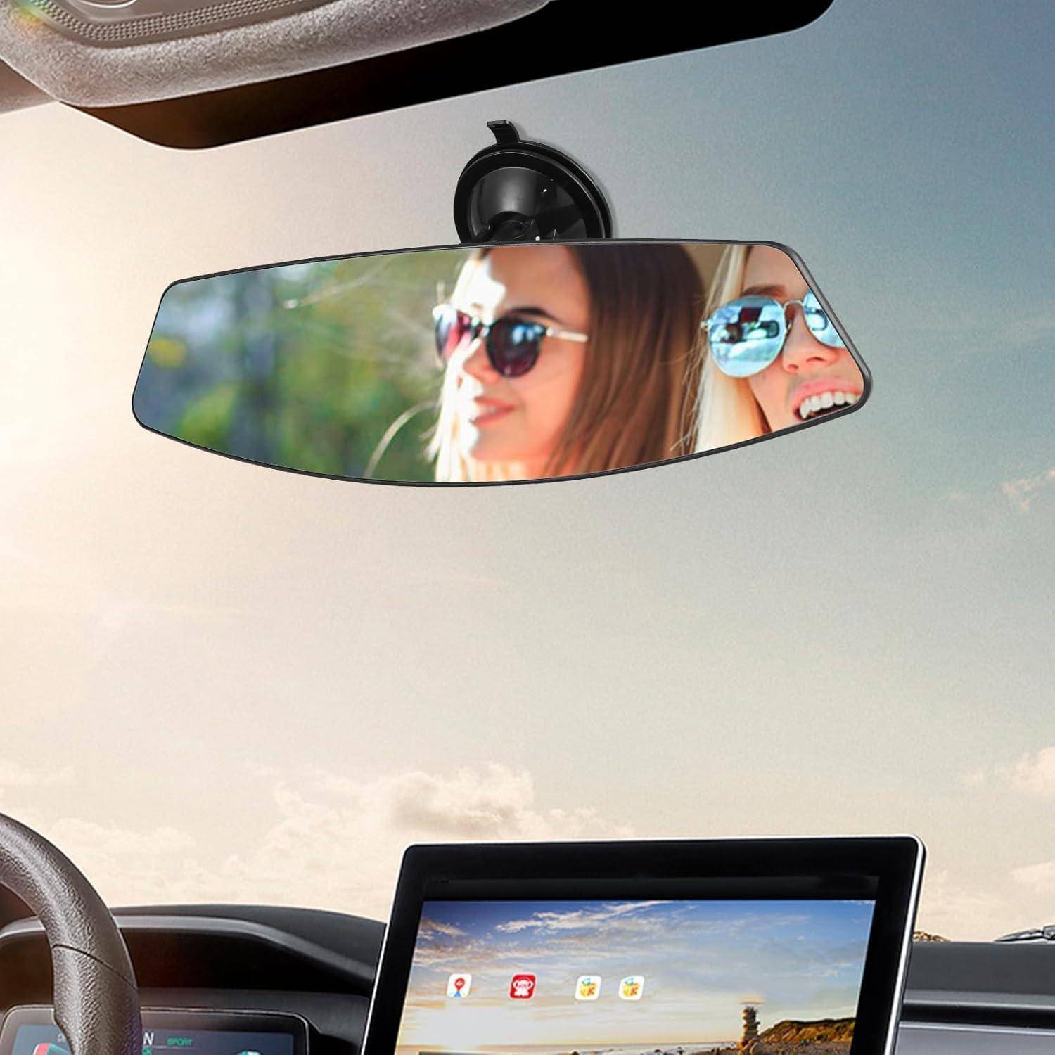 Autoinnenraum aus der Perspektive der Rückbank, mit zwei Frauen mit Sonnenbrillen, die sich im Rückspiegel spiegeln, und einem Touchscreen-Dashboard darunter.