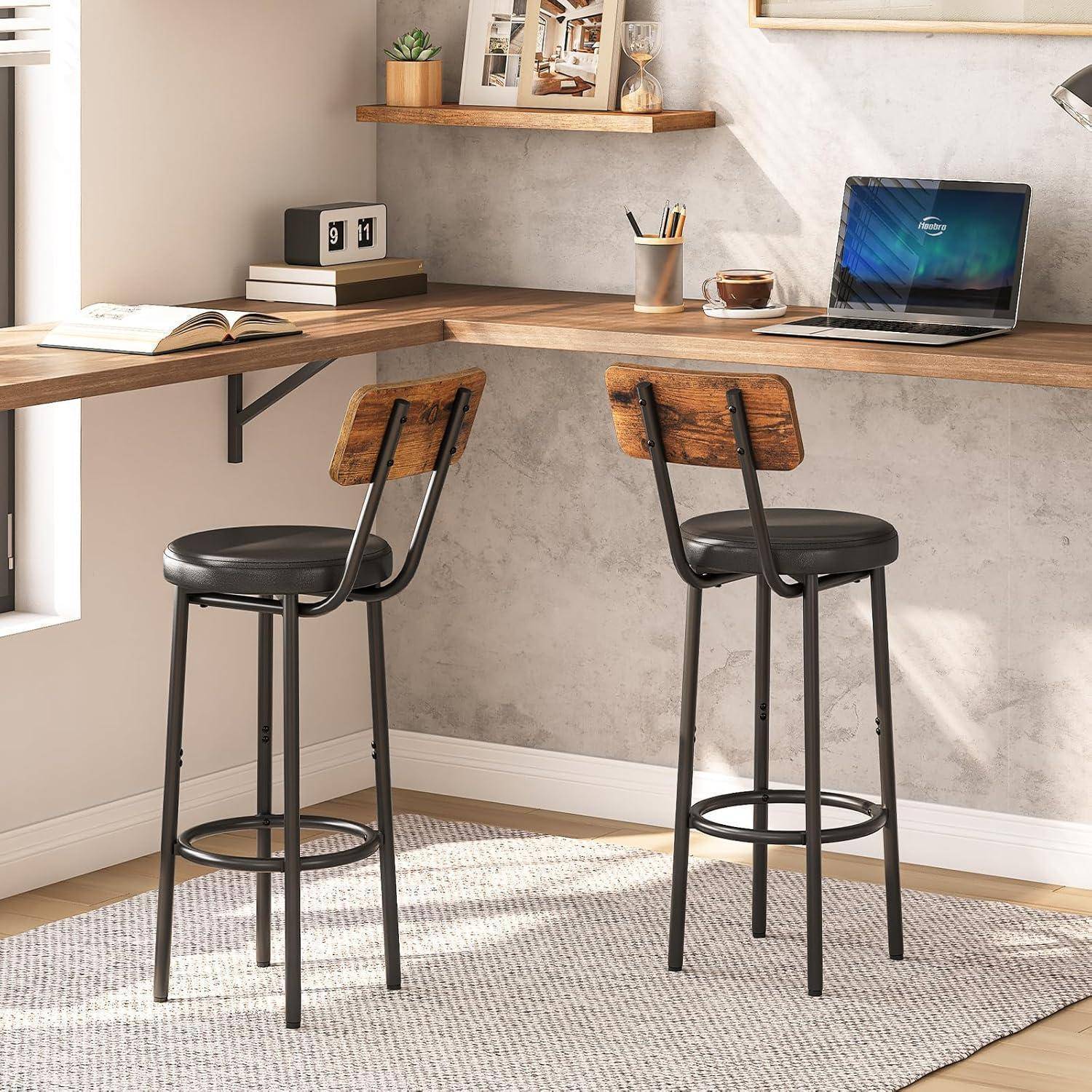 Modernes Eckbüro mit an der Wand montiertem Holzschreibtisch, zwei hohen Hockern, einem aufgeschlagenen Buch, Laptop, Uhr und kleiner Regaldekoration.