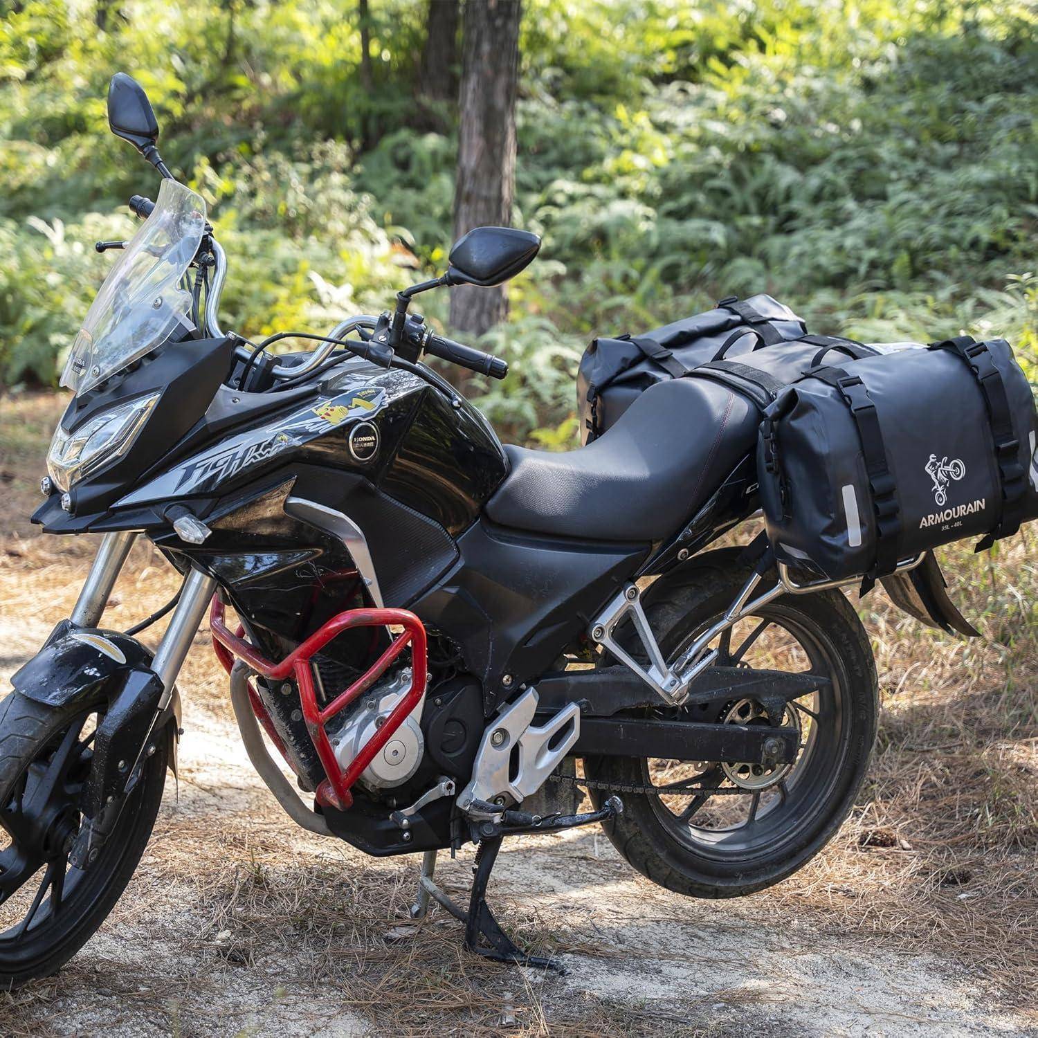 Schwarzes Tourer-Motorrad, das auf einem Waldwanderweg im Freien geparkt ist und mit Seitenkoffern und Gepäcktaschen für Reisen ausgestattet ist.