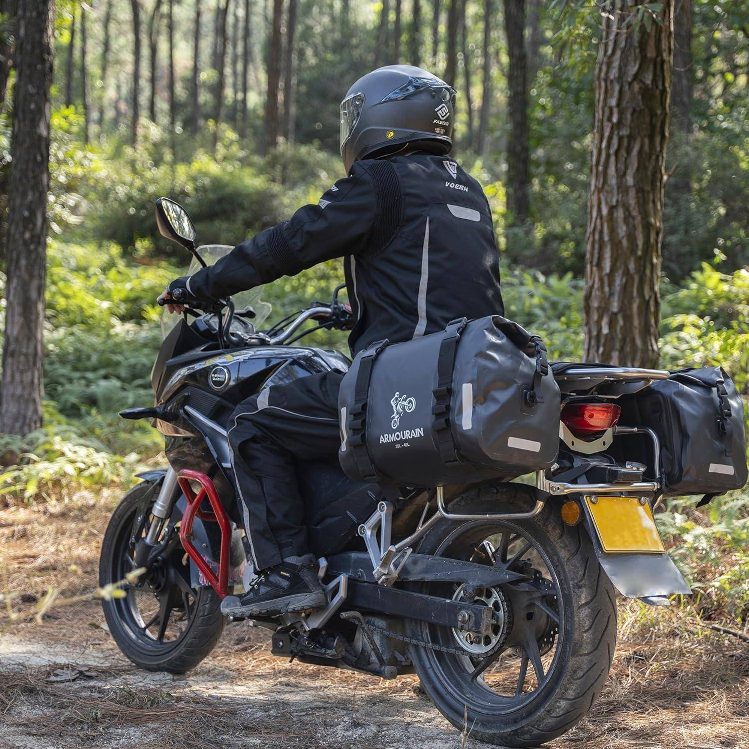 Motorradfahrer in voller Ausrüstung fährt ein schwarzes Adventure-Motorrad auf einem Waldweg und trägt Seitenkofferträger für Reisen.