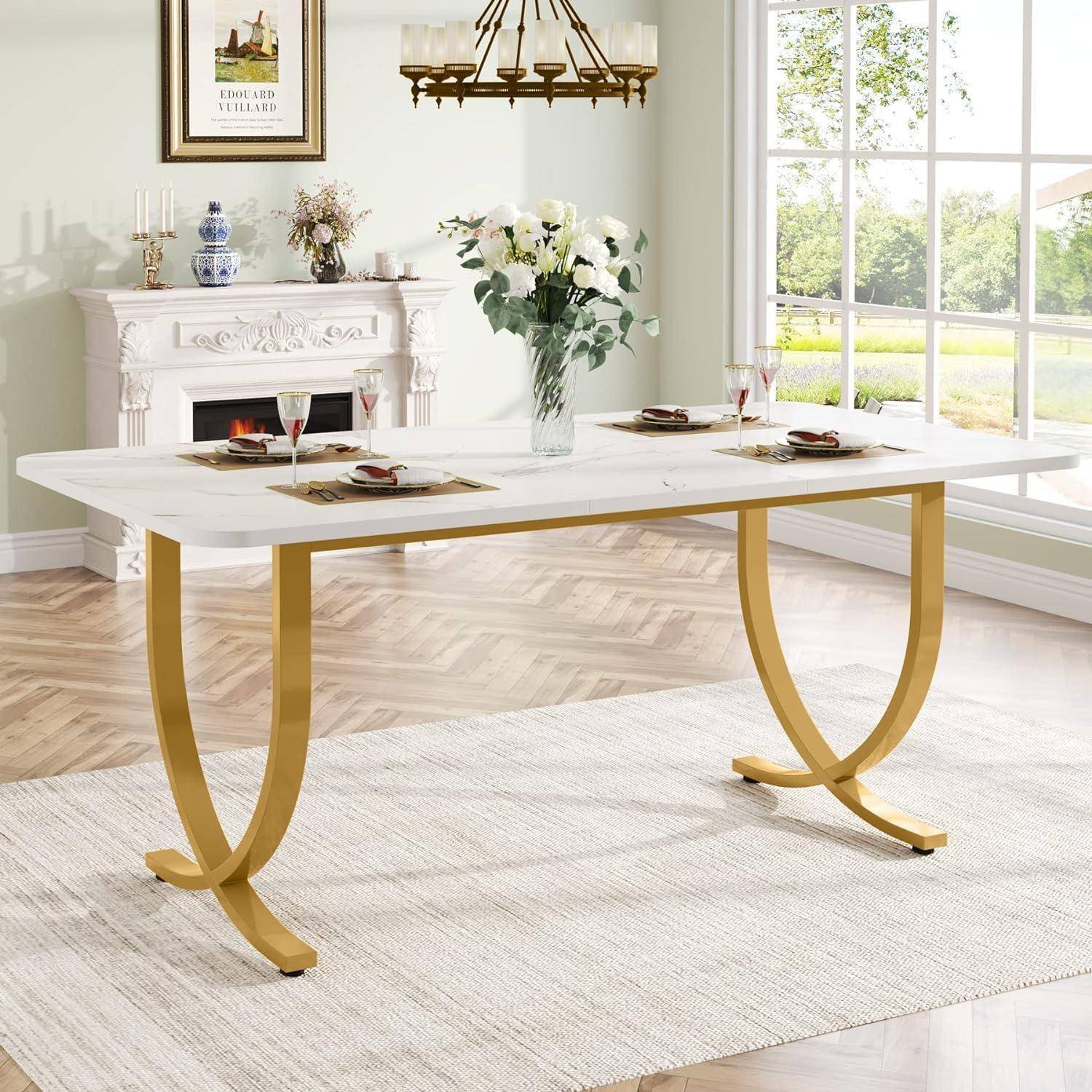 Ein weißer Esstisch mit goldenen geschwungenen Beinen steht in einem hellen, eleganten Esszimmer in der Nähe eines Kamins und eines großen Fensters.