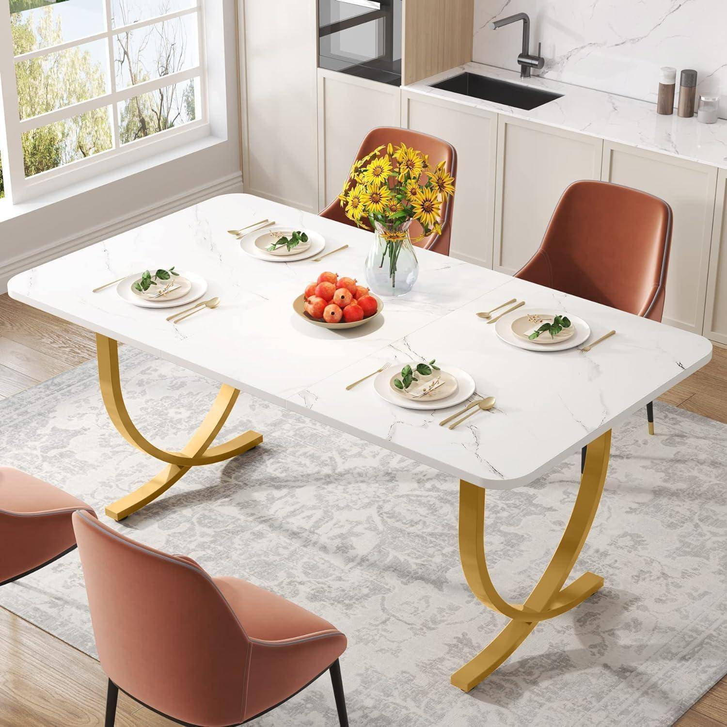 Modernes Esszimmer mit weißem Tisch für vier Personen, rosafarbenen Stühlen, einer Vase mit gelben Blumen und einer Obstschale in der Nähe einer Küchentheke und eines Fensters.