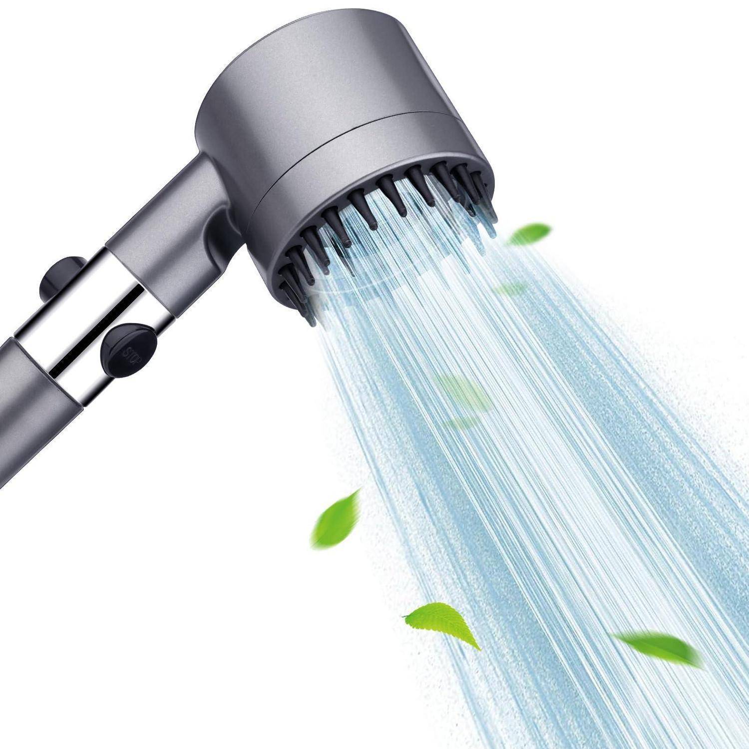 Duschkopf, der einen breiten Wasserstrom mit einigen grünen Blättern, die hindurchfliegen, auf weißem Hintergrund sprüht.