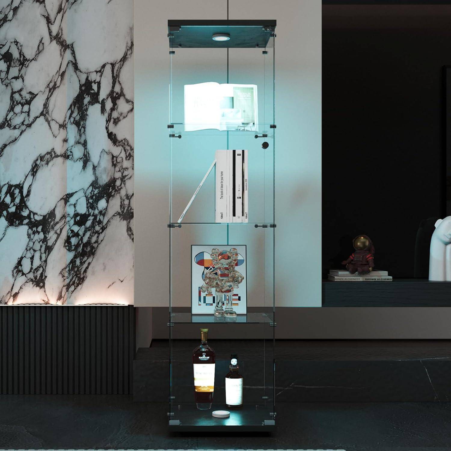 Ein hohes gläsernes Vitrinenschrank mit beleuchteten Regalen, in dem Bücher, ein gerahmtes Kunstwerk und Flaschen ausgestellt sind, vor einer Marmerwand in einem modernen Interieur.