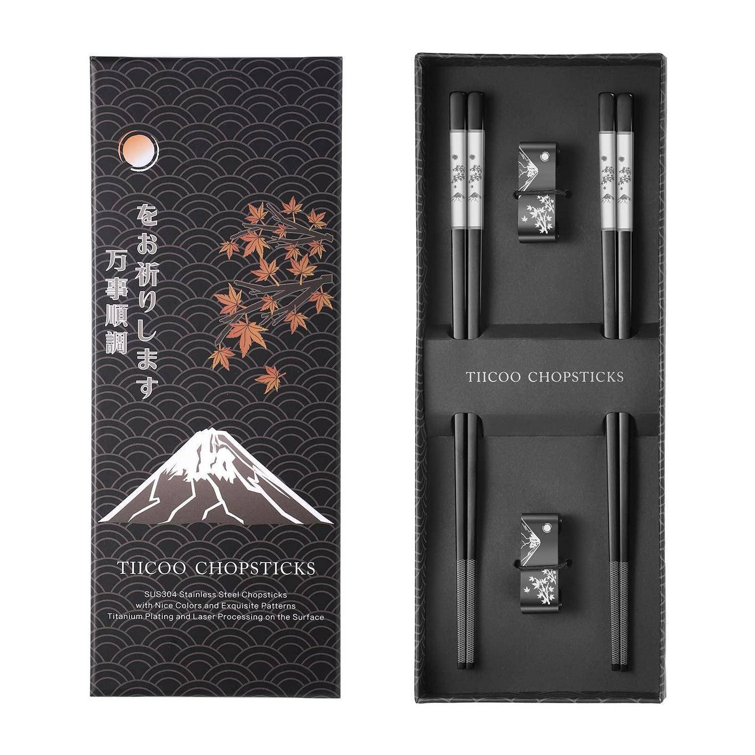 Schwarze Geschenkbox für TICOO-Stäbchen mit dem Berg Fuji, Ahornblättern und japanischem Text auf der Vorderseite; innen befinden sich zwei Paar schwarze Stäbchen mit Blumenstänhern.