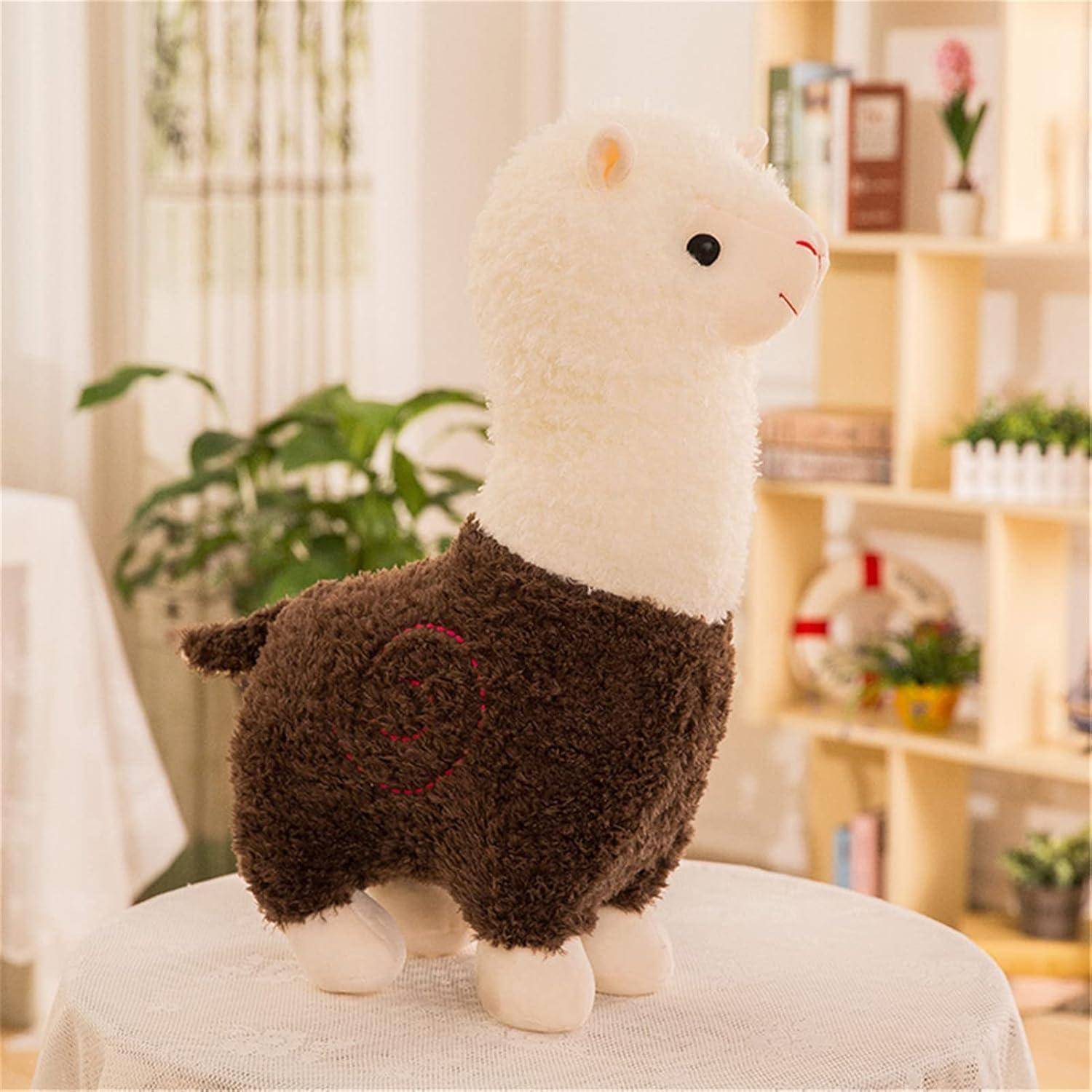 Ein flauschiges weiß-braunes Alpaka-Plüschtier steht auf einem Tisch in einem hellen, gemütlichen Zimmer mit Pflanzen und Regalen im Hintergrund.