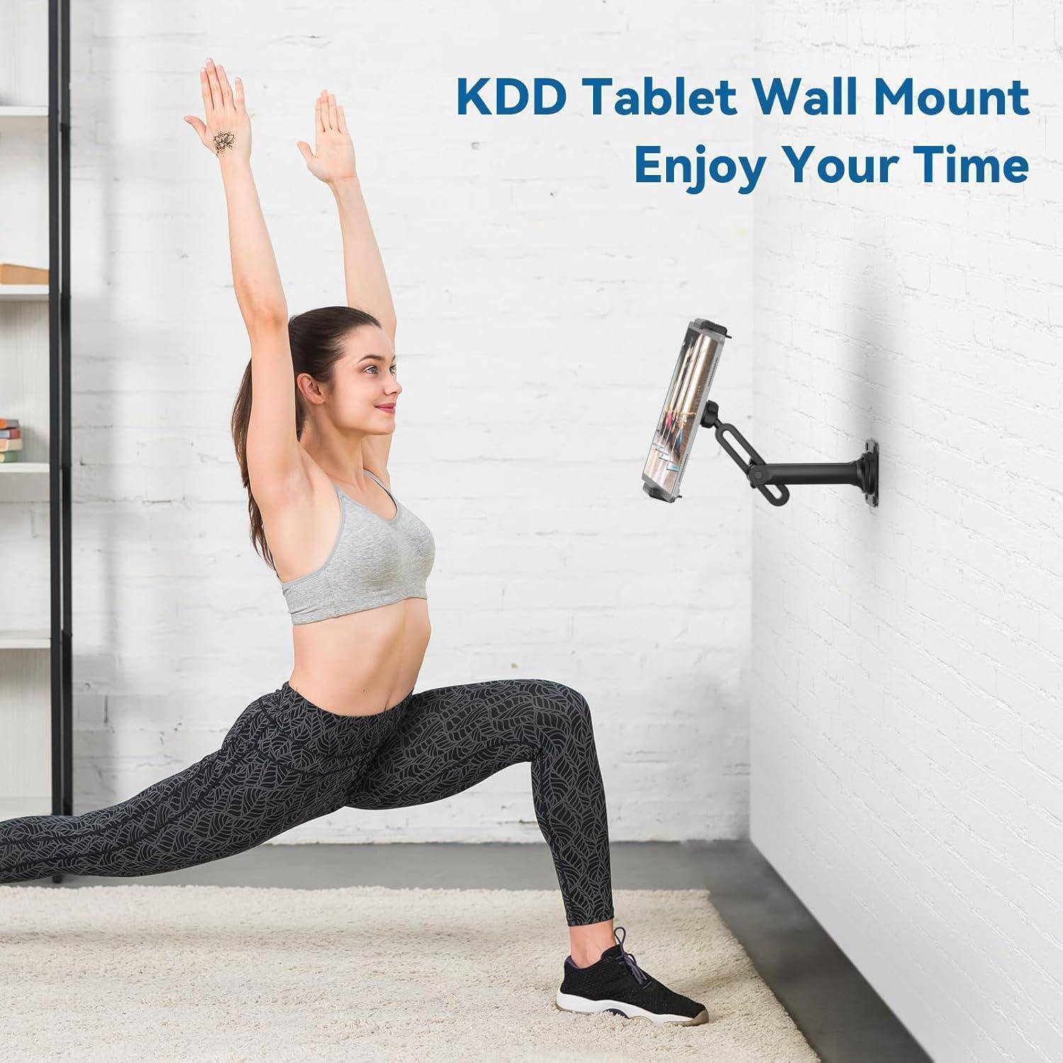 Frau macht eine Yoga-Ausfallschritt-Pose in einem Zimmer, blickt auf einen an der Wand angebrachten Tablet-Halter; der Text lautet „KDD Tablet Wandhalterung Genießen Sie Ihre Zeit".