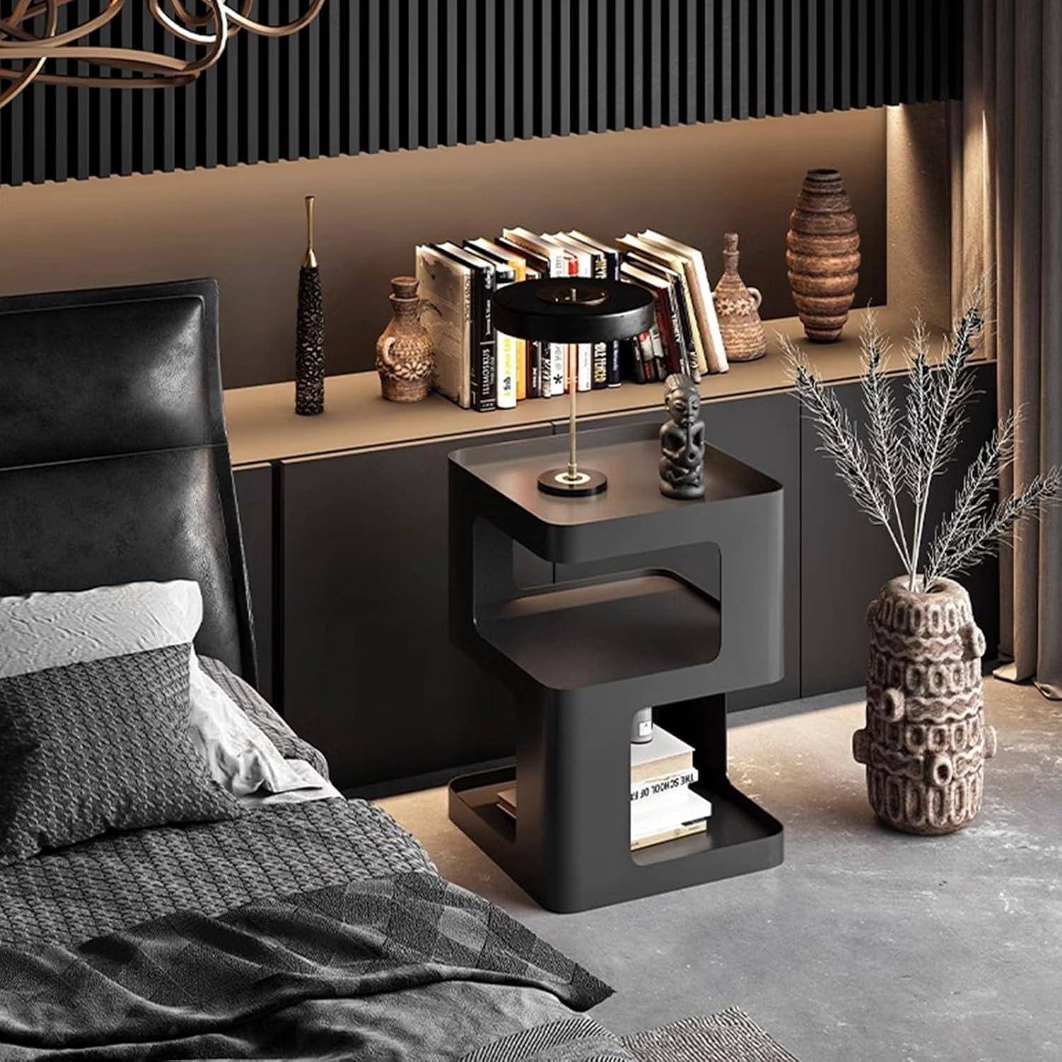 Modernes Schlafzimmer mit schwarzem Bett, Nachttisch, Büchern und dekorativen Vasen, mit einer skulpturalen schwarzen Lampe und hoher Trockenblumenanordnung.