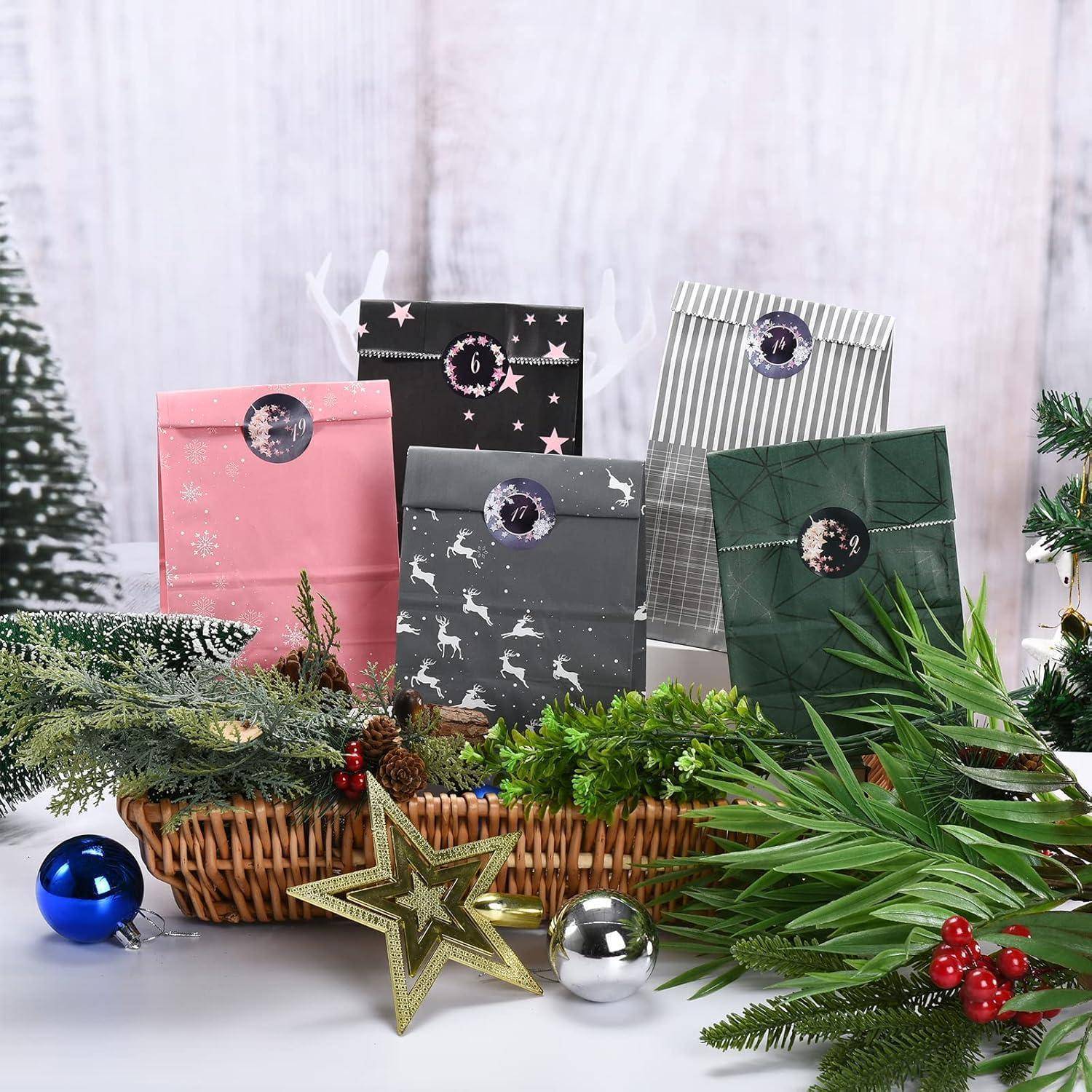 Sortierte festliche Geschenktüten in Pink, Schwarz, Grau und Grün hinter einem Korb mit Immergrünzweigen, Sternornament und Weihnachtskugeln.