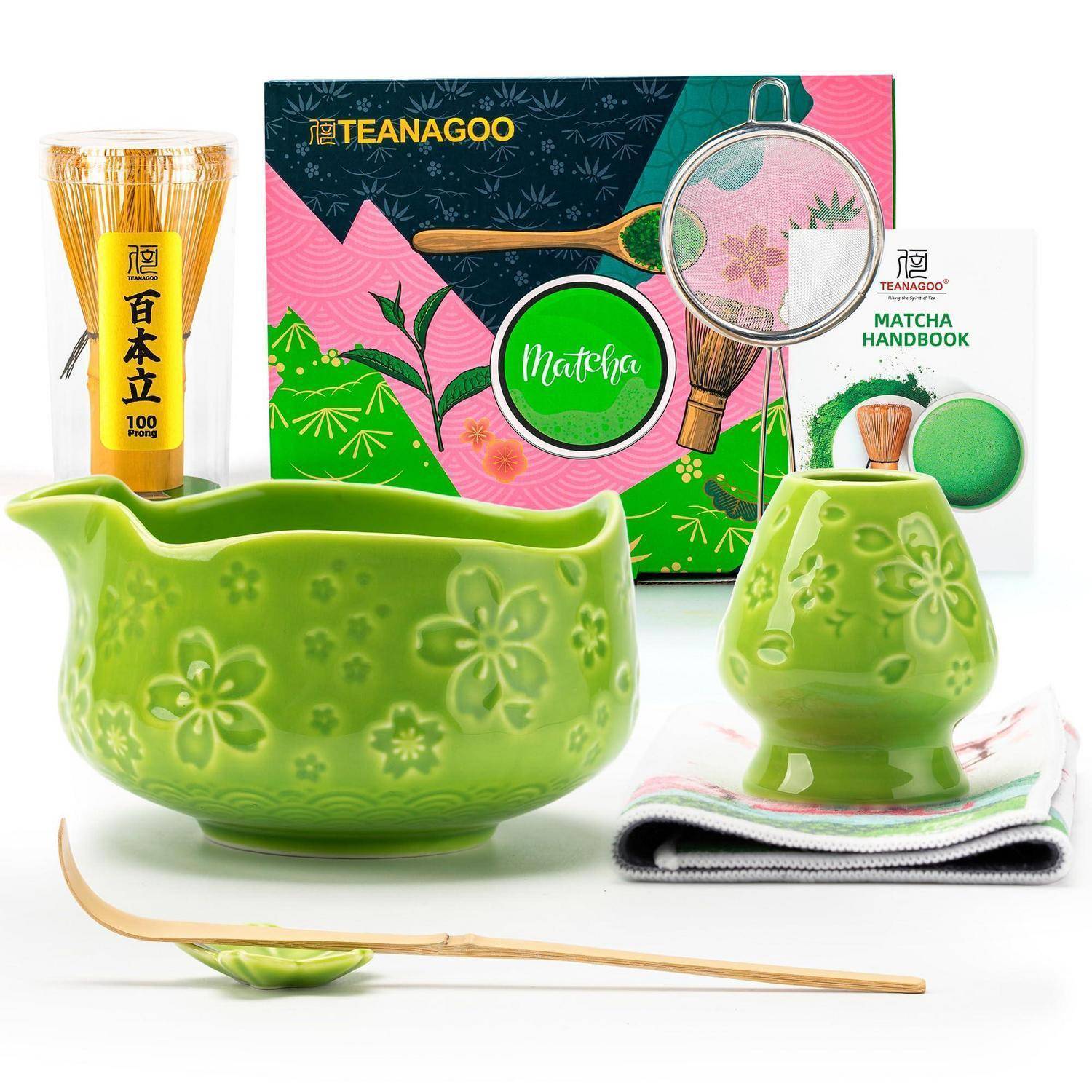 Matcha-Tee-Set mit einer grünen Keramikschale, Schneebesen-Ständer, Bambuslöffel und Teedose, angeordnet mit einer „Matcha Handbook