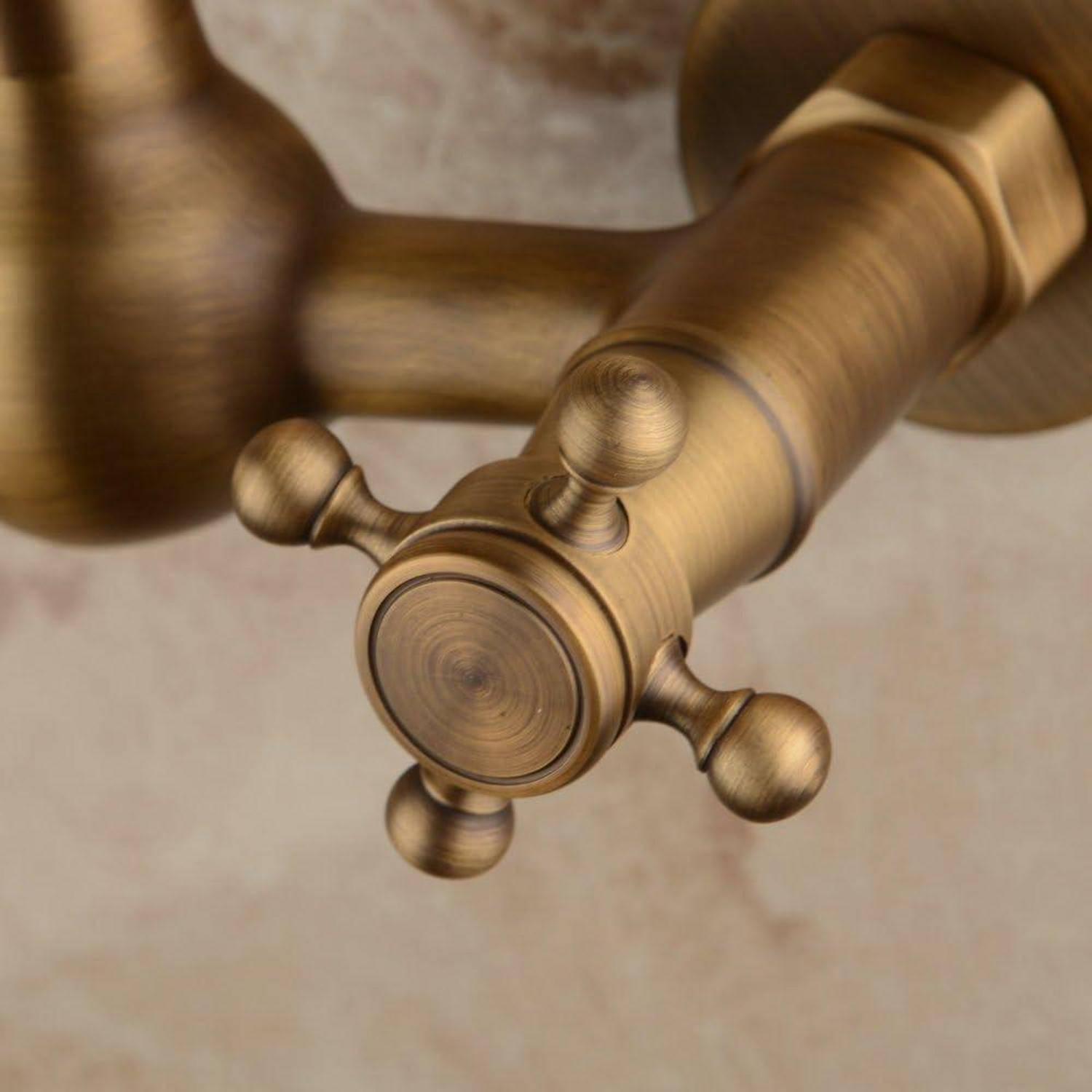 Nahaufnahme eines Messingduschventilgriffs mit einem kreuzförmigen Knauf und runder Grundplatte an einer gekachelten Wand.