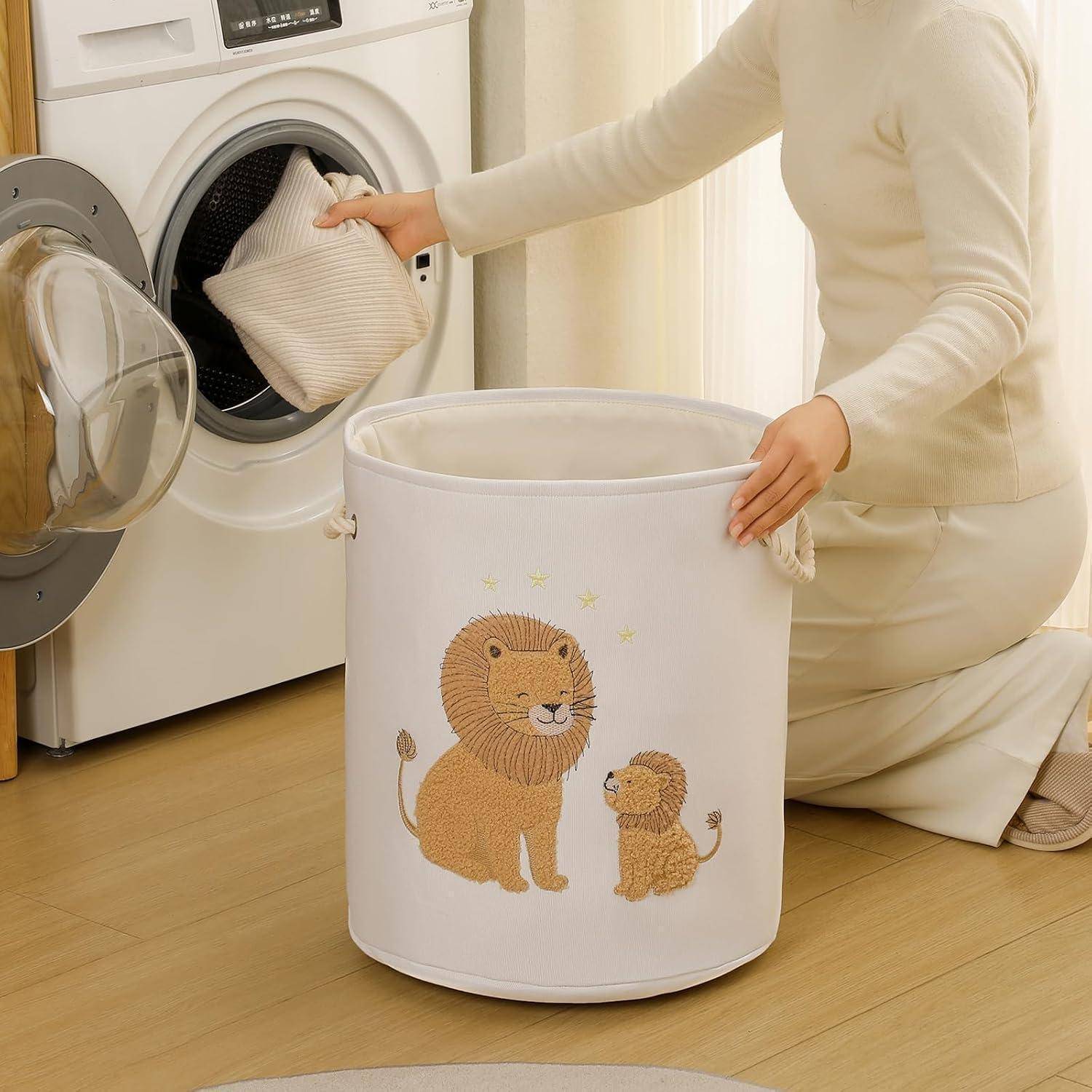 Eine Person lädt ein Kissen in eine Frontlader-Waschmaschine neben einem weißen Wäschekorb mit einem Löwe-und-Junges-Design.