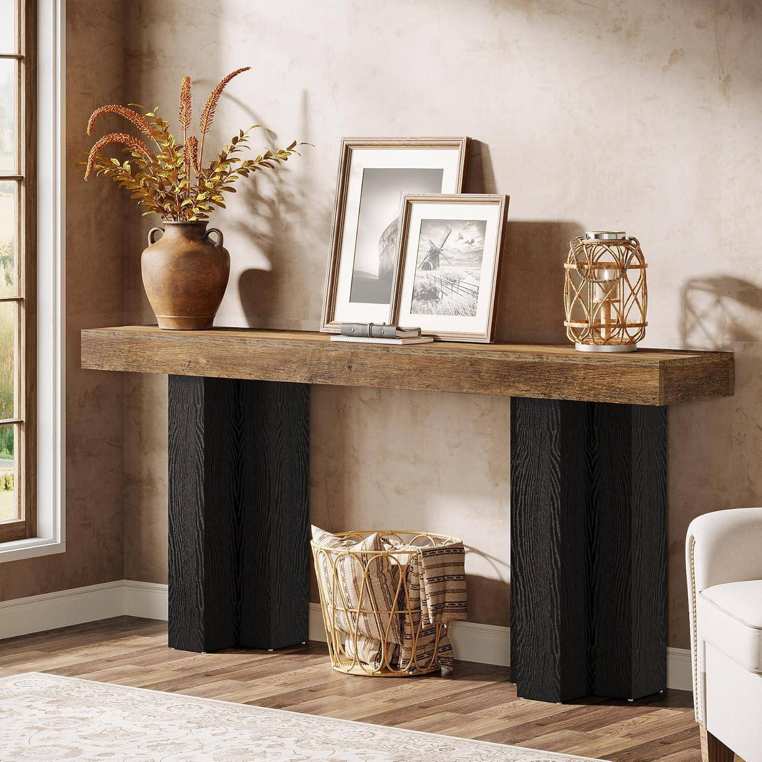 Rustikaler Holzkonsoltisch an einer beigen Wand mit Bilderrahmen, einer Vase mit Trockenblumen, einer Laterne und einem geflochtenen Korb darunter.