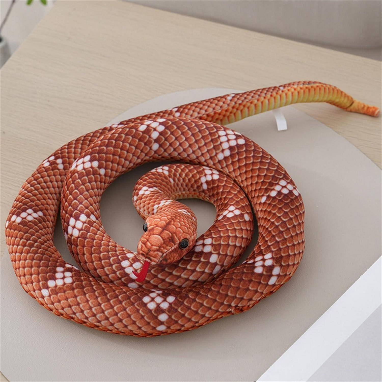Aufgerollte orange-weiße Schlangenfigurine mit roter Zunge, ausgestellt auf einer hellfarbigen Oberfläche.