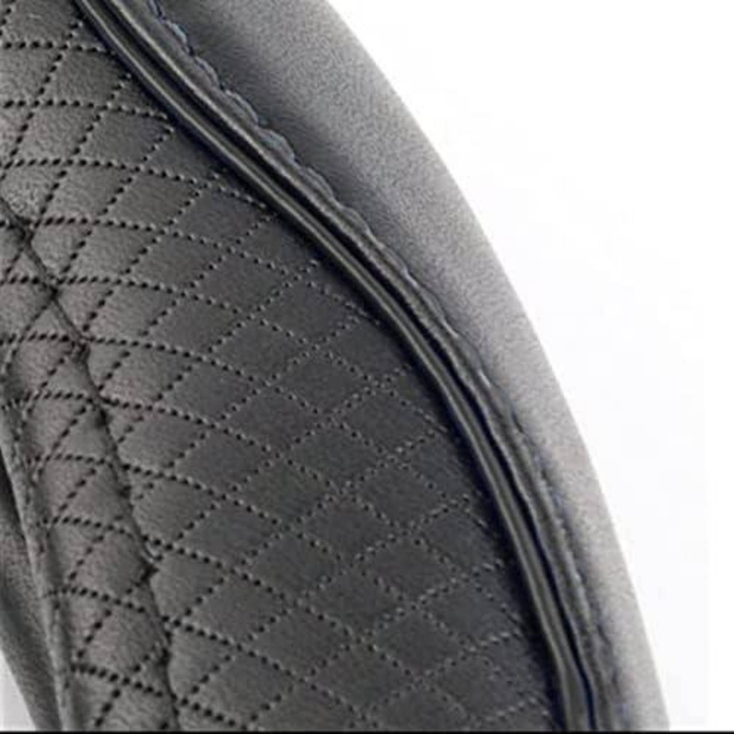 Nahaufnahme einer schwarzen gesteppten Leder- oder Vinylsitzkante mit geschwungener Polsterung vor weißem Hintergrund.