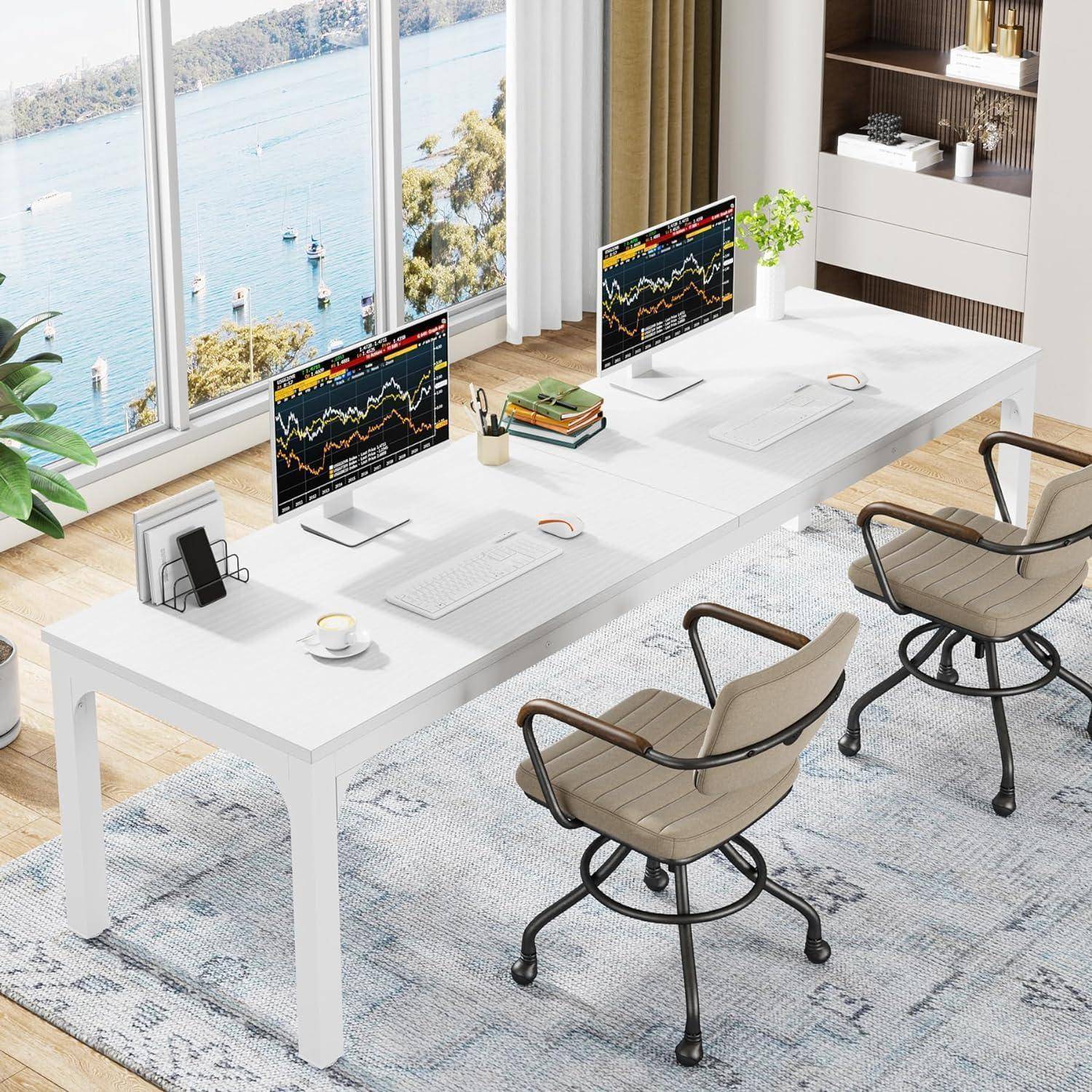 Modernes Büro mit langem weißem Schreibtisch, zwei Stühlen und zwei Monitoren, die Aktienmarktdiagramme anzeigen, neben großen Fenstern mit Blick auf das Wasser.