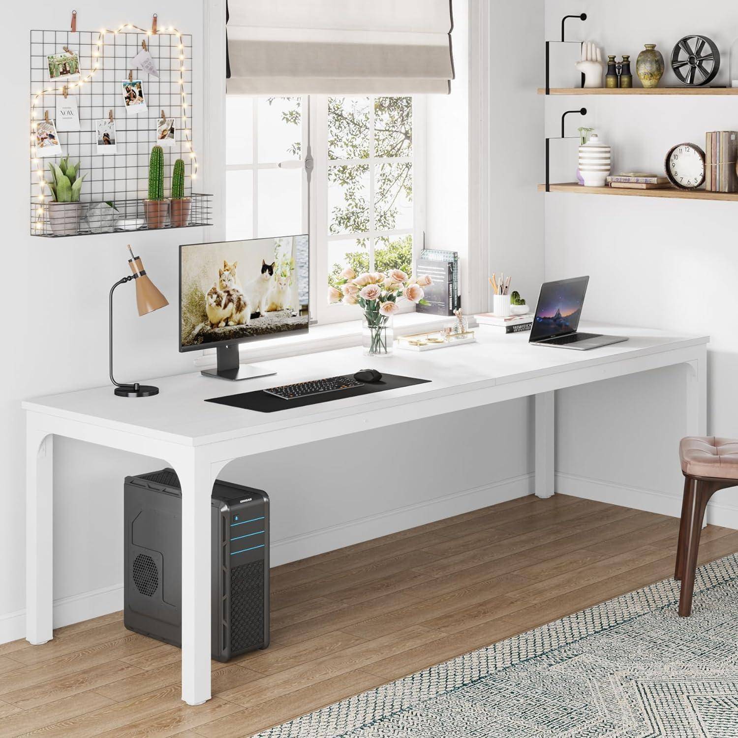 Modernes Homeoffice mit weißem Schreibtisch, Desktop-Monitor, Laptop, Lampe und Dekoration neben einem Fenster und Wandregalen.