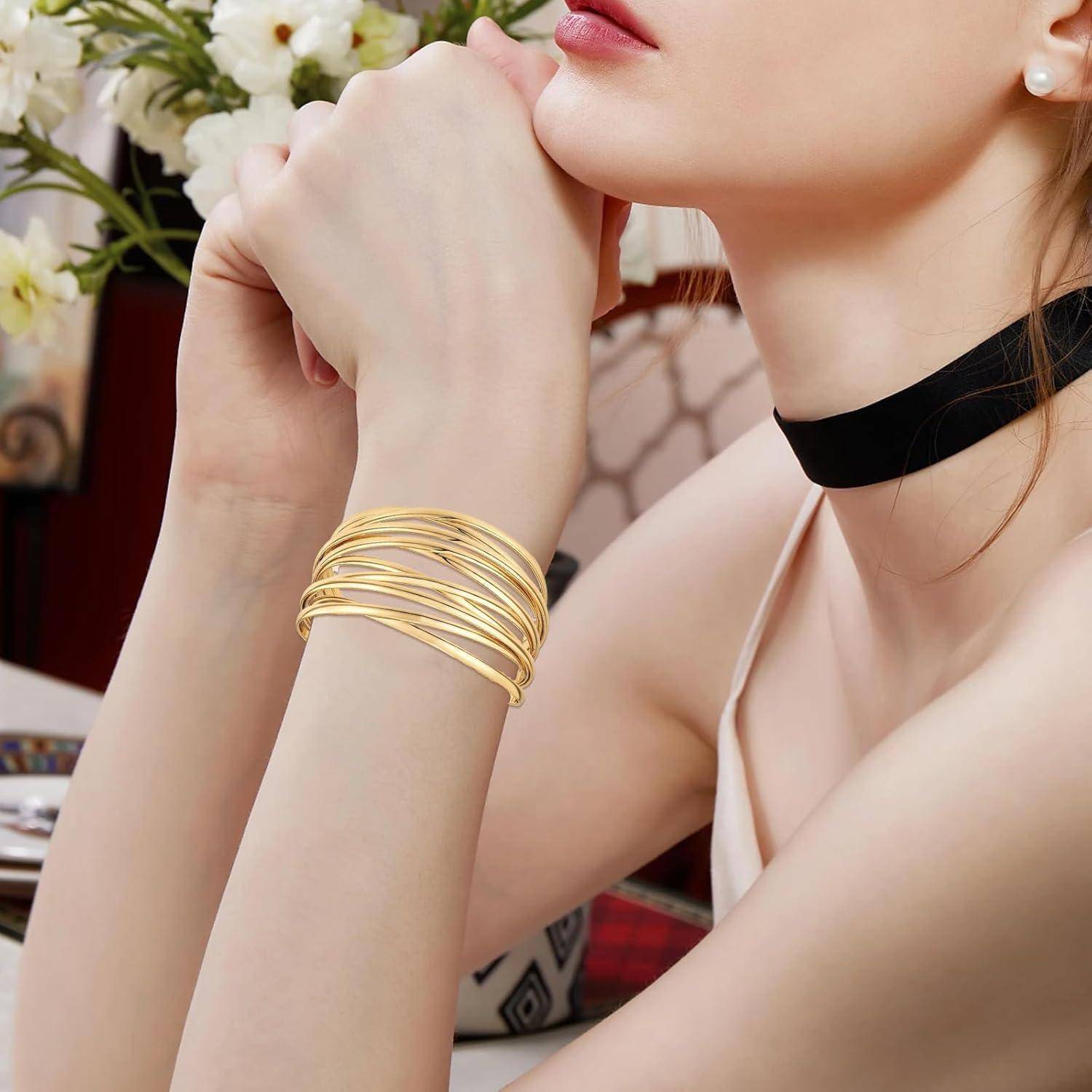 Nahaufnahme einer Frau, die ihr Kinn auf ihren Händen ablegt, trägt ein schwarzes Choker und gestapelte goldene Armreifen.