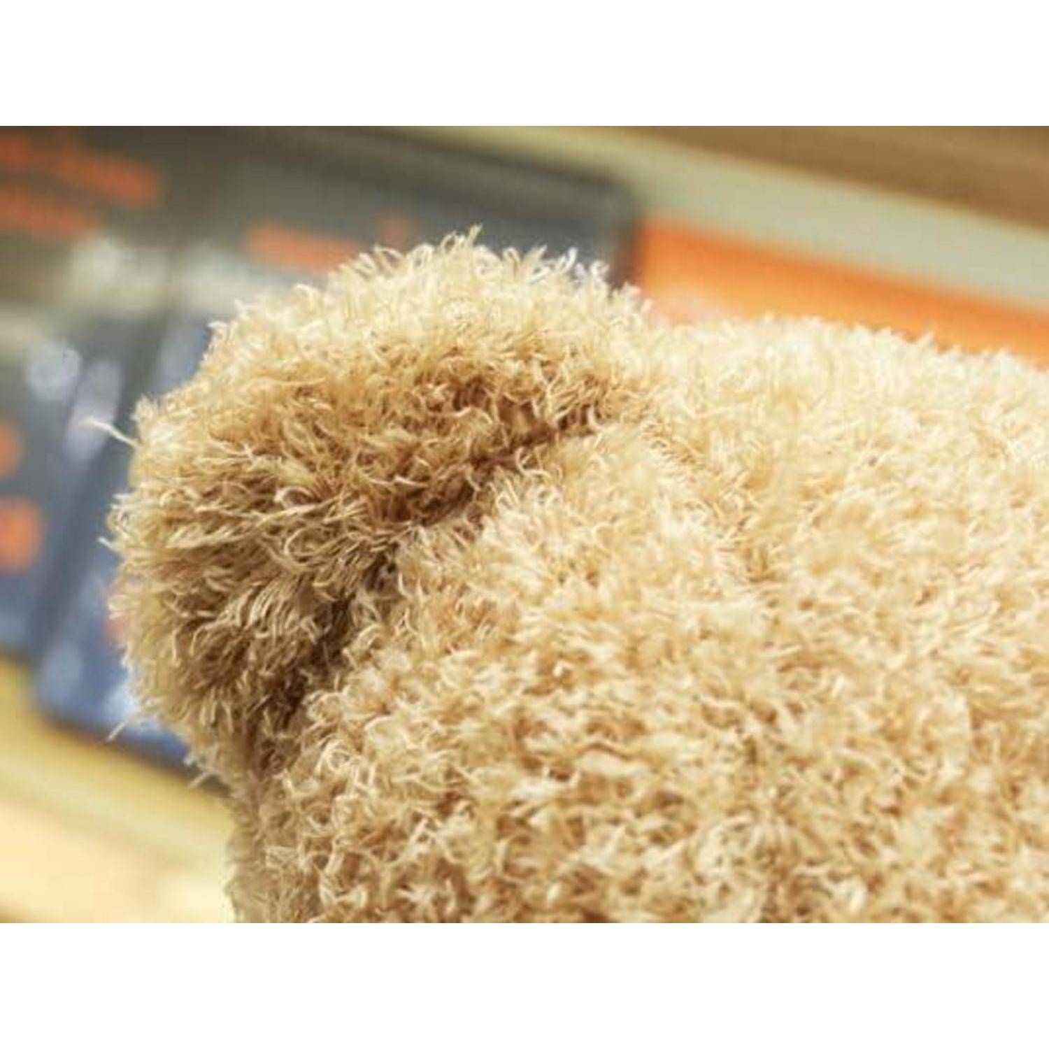 Nahaufnahme eines flauschigen beigefarbenen Teddybären, das sein Ohr und das strukturierte Fell gegen einen unscharfen Hintergrund zeigt.