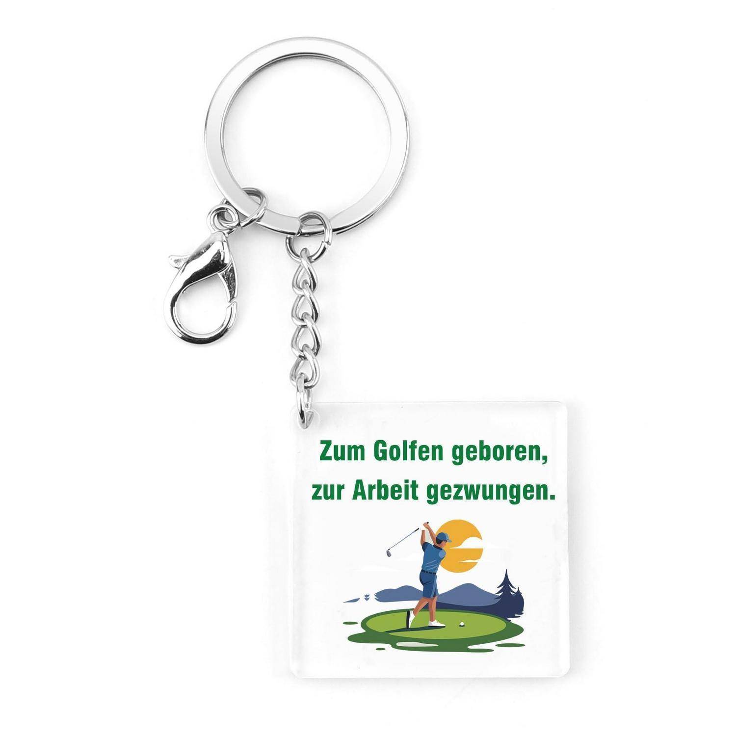 Schlüsselanhänger mit quadratischem weißem Etikett, auf dem der deutsche Text „Zum Golfen geboren, zur Arbeit gezwungen.