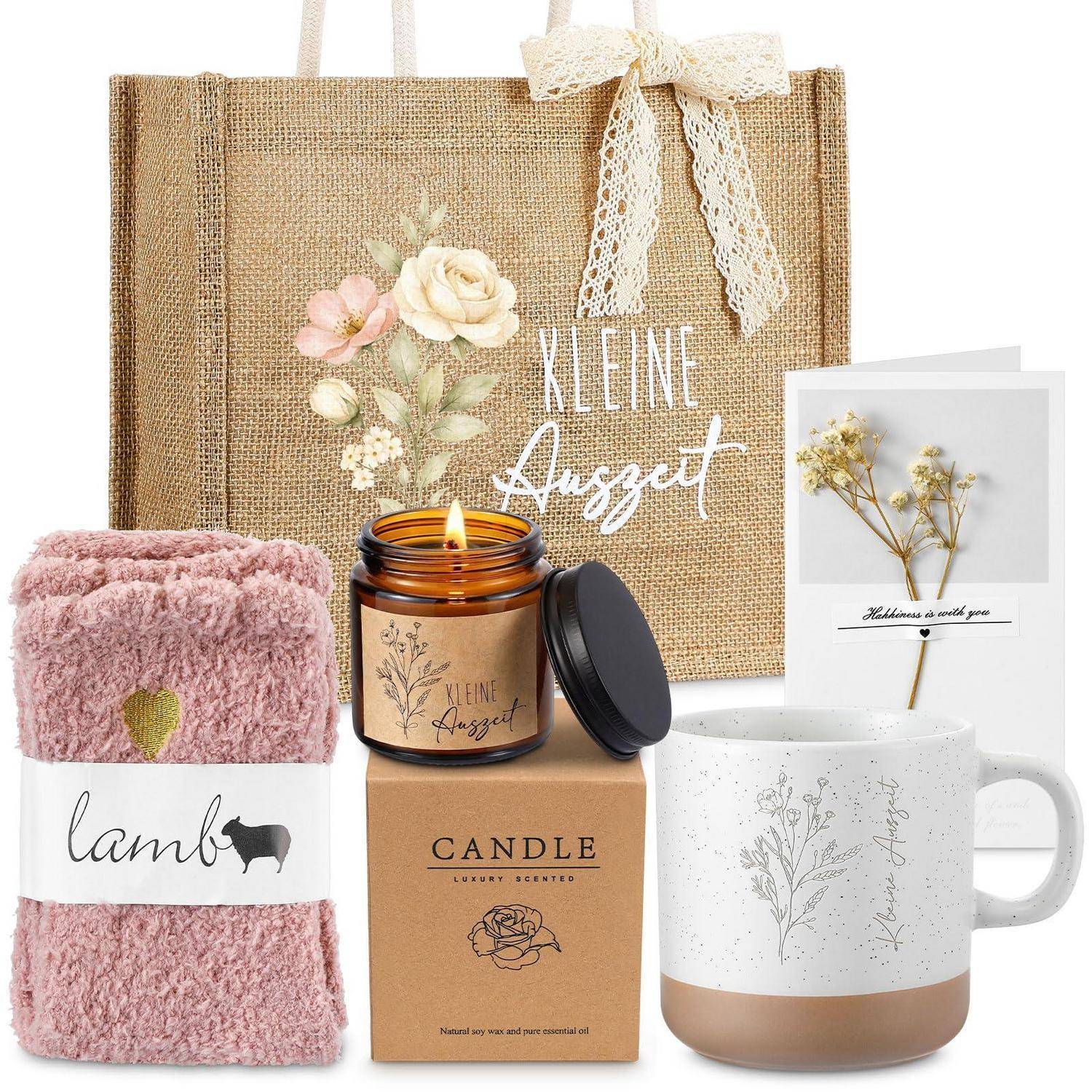 Geschenkset mit Juteverpackung, rosafarbener Decke, brennender Kerze in einer Box, Keramiktasse und Karte, alles im sanften Blumenmotiv-Thema „Kleine Auszeit