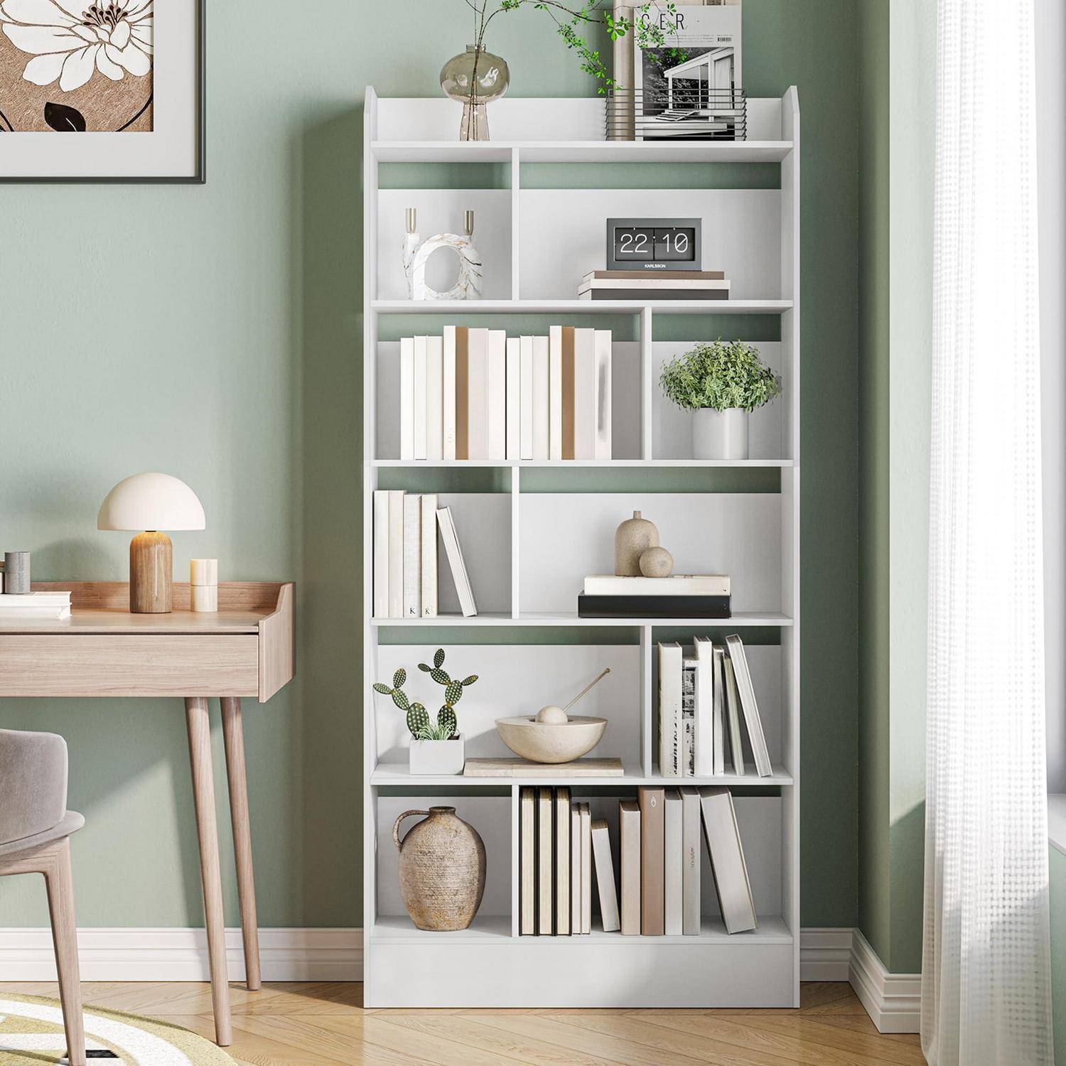 Ein weißes Bücherregal, das mit Büchern, Pflanzen, Dekoration und einer digitalen Uhr in einer hellgrünen Arbeitszimmerecke neben einem Schreibtisch und Stuhl eingerichtet ist.