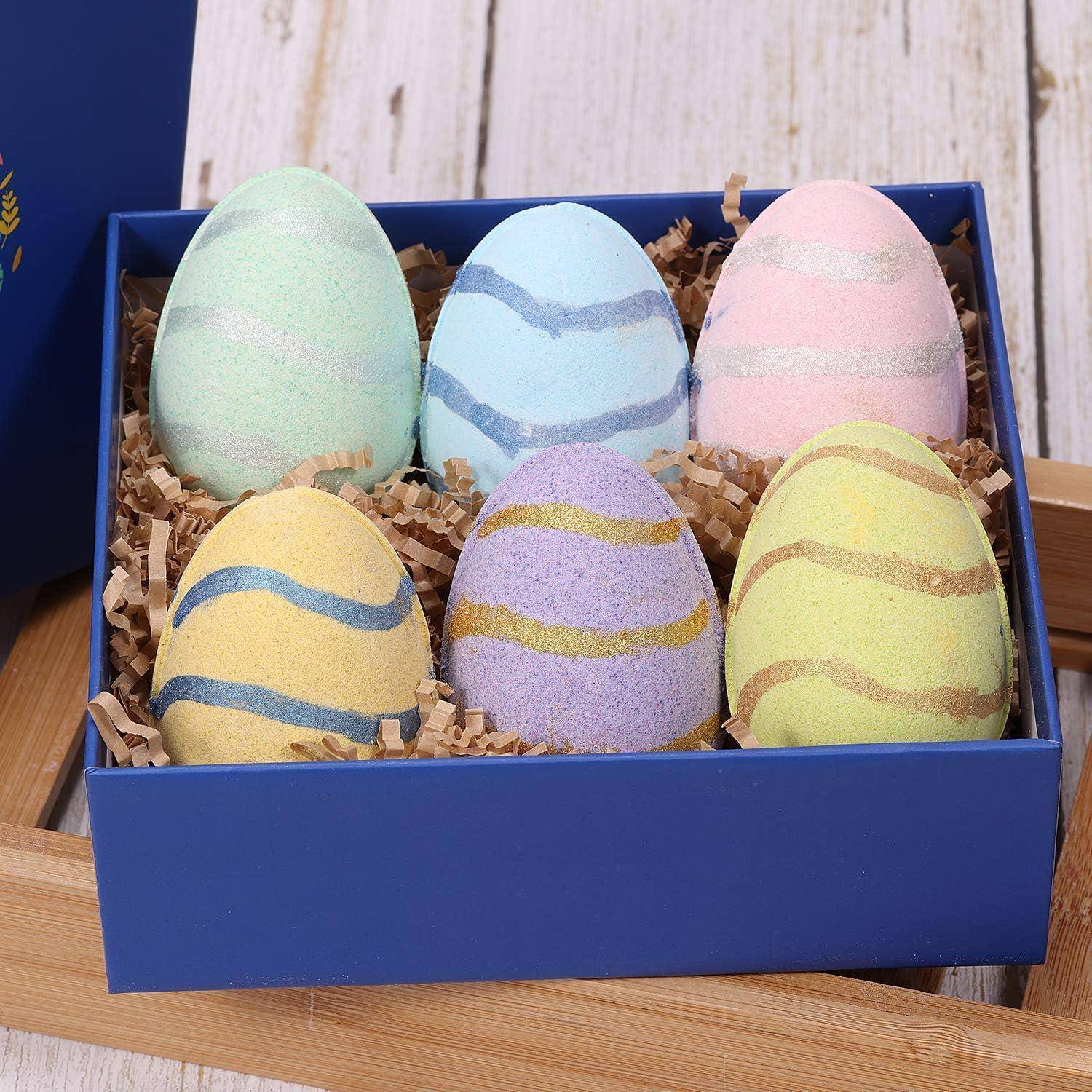Eine blaue Schachtel gefüllt mit sechs pastellfarbenen, gestreiften dekorativen Ostereiern, die in zerrissenes Papier gebettet sind.