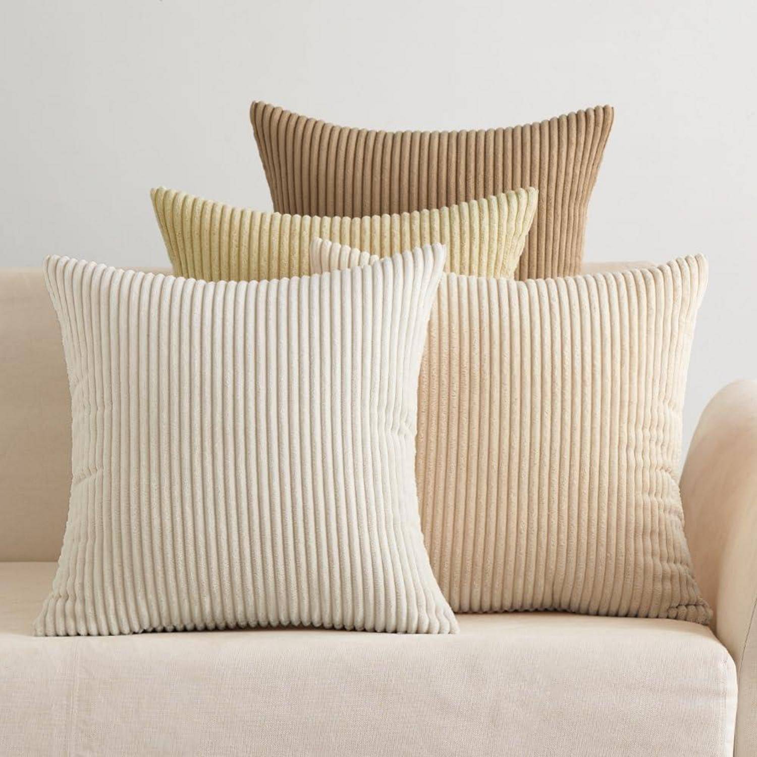 Vier gerippte Strukturkissen in Creme und Beige, arrangiert auf einem beigefarbenen Sofa.