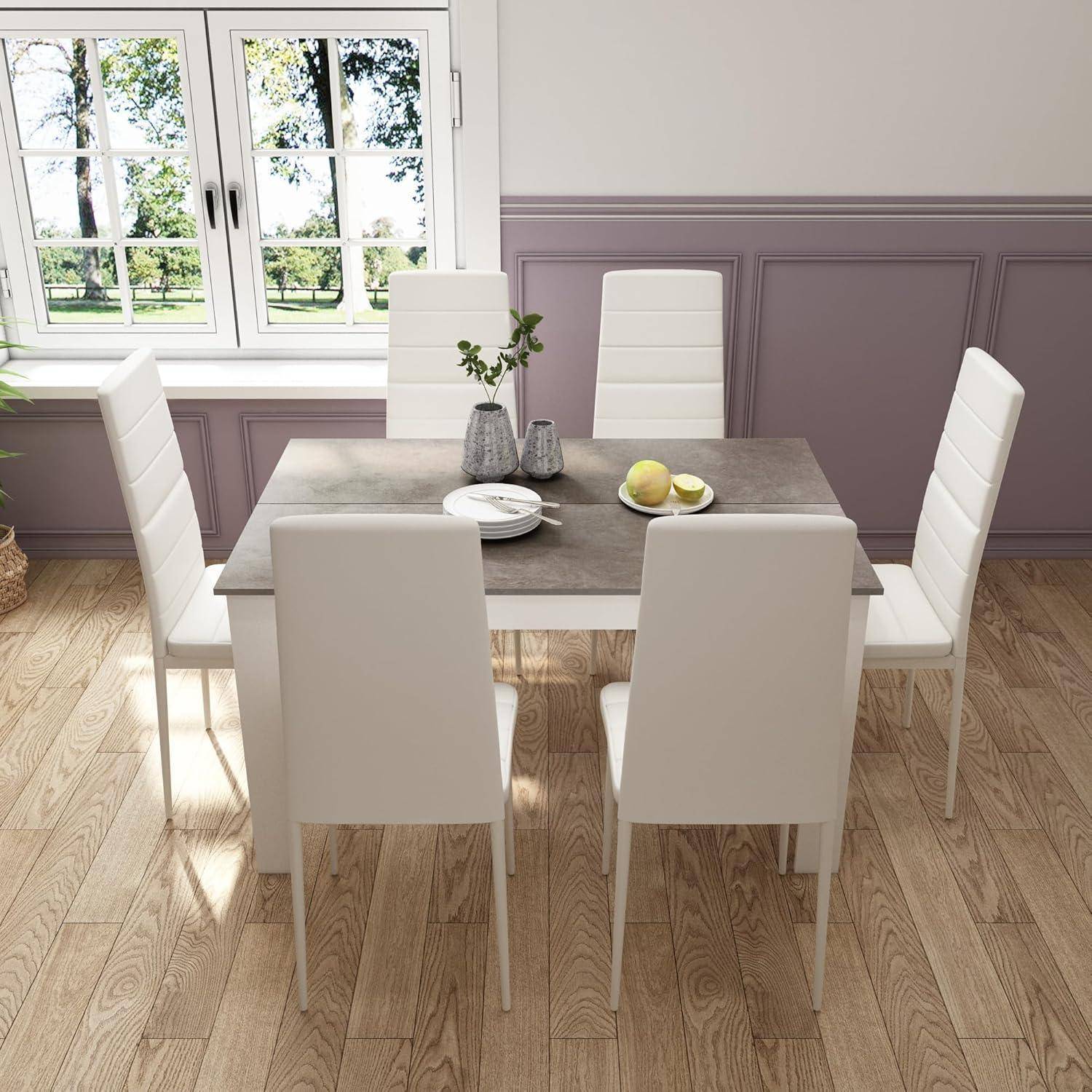 Modernes Esszimmer mit quadratischem Tisch, sechs weißen Stühlen und einfachem Tischbesteck neben einem hellen Fenster.