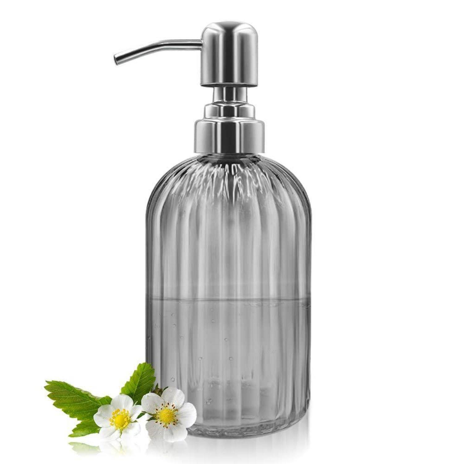 Transparente Seifenspender-Flasche mit Rippenmuster und Metallpumpe, auf weißem Hintergrund mit kleinen weißen Blüten und grünen Blättern an der Basis dargestellt.