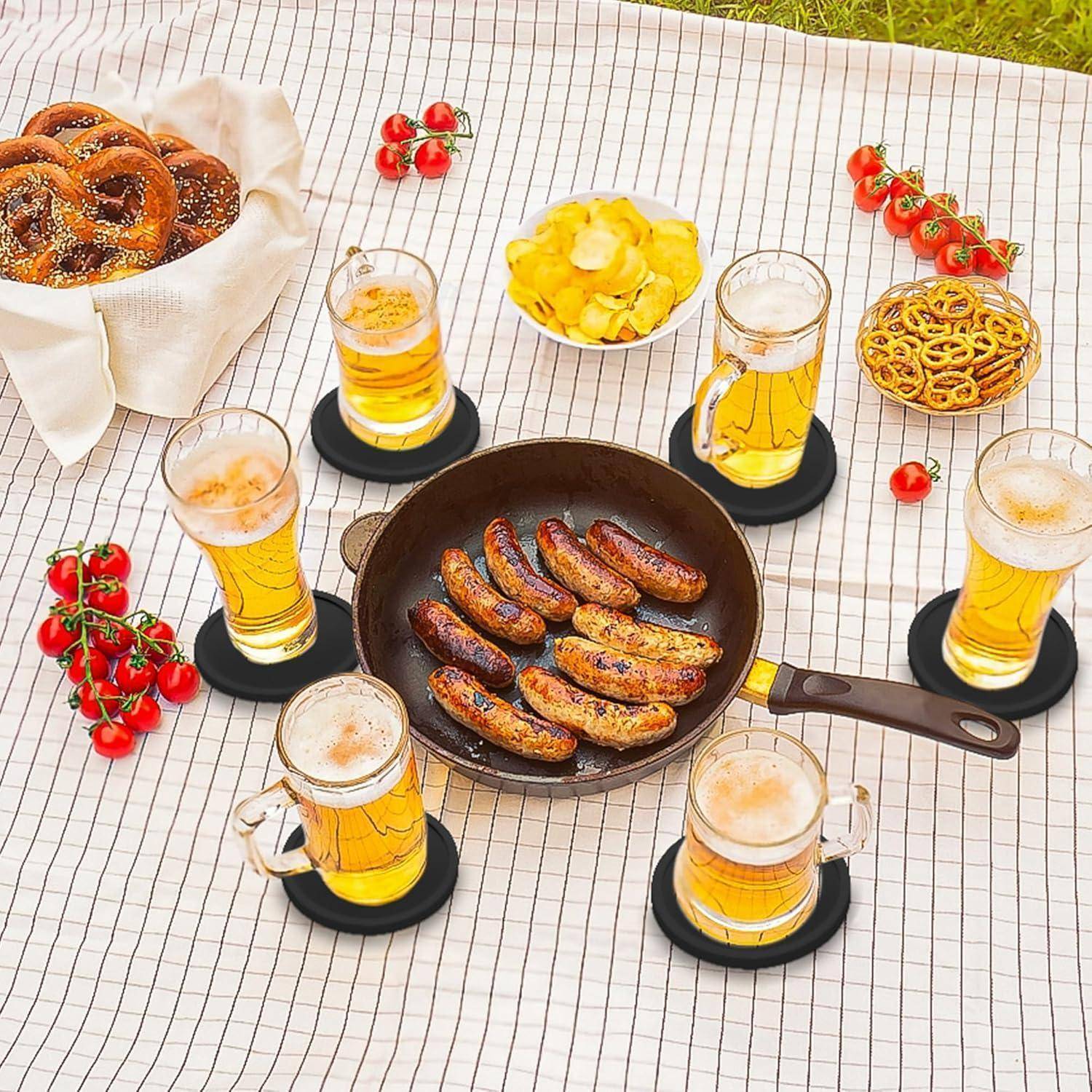 Draufsicht auf einen Tisch mit einer Pfanne mit gegrillten Würstchen, umgeben von Biergläsern und Schüsseln mit Brezeln und Chips, mit Kirschtomaten und einem Korb mit Brot.