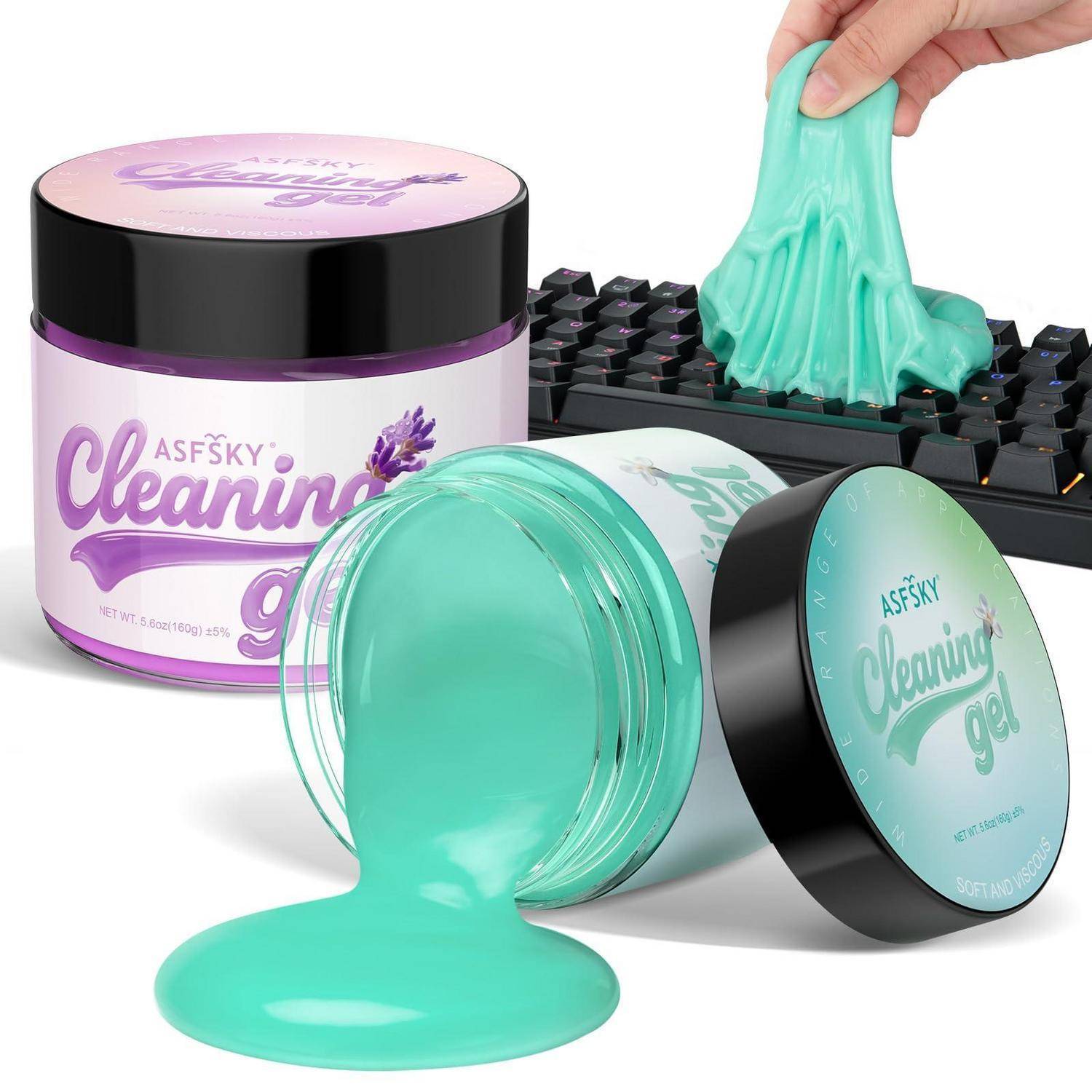 Behälter mit mintgrünem Reinigungsgel, wobei ein Glas offen ist und das Gel auf eine Tastatur tropft, die von einer Hand angehoben wird.