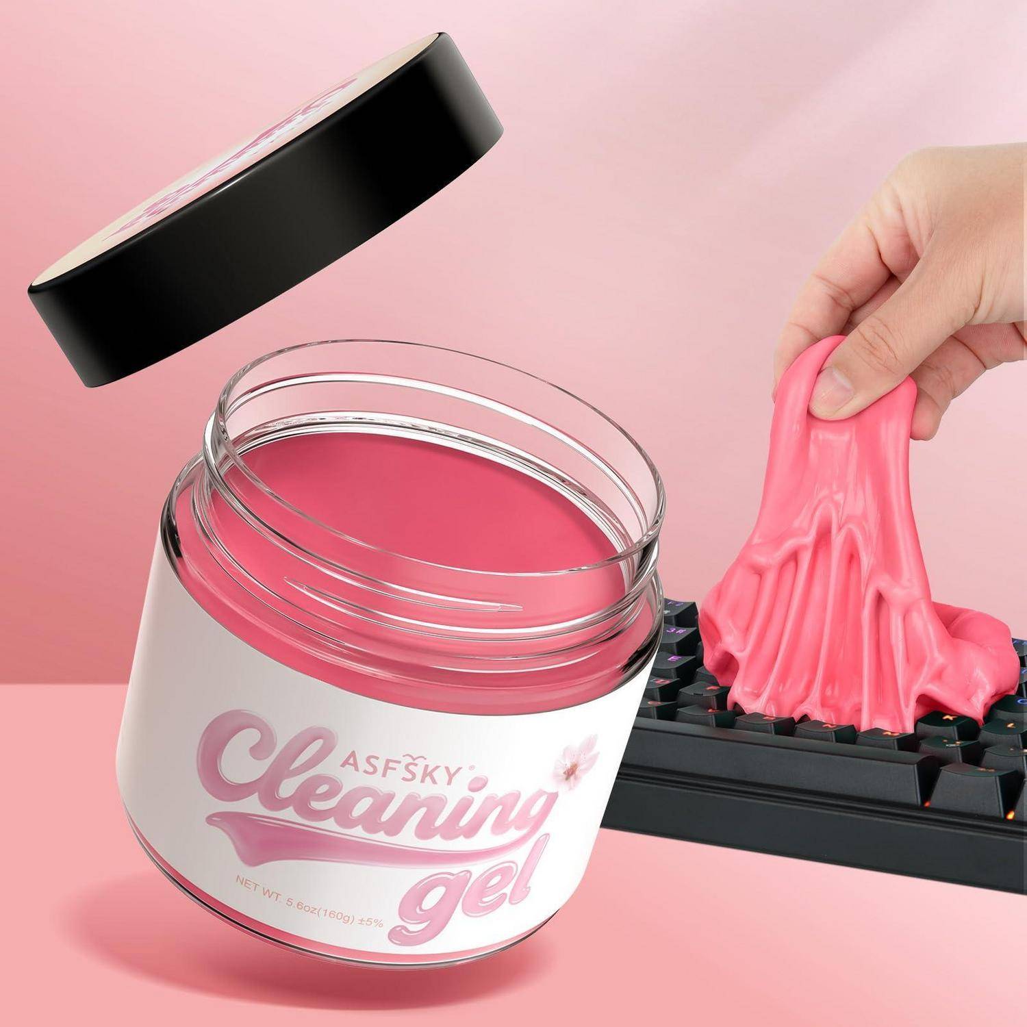 Glas mit rosa 'Reinigungsgel' gezeigt mit einer Hand, die das klebrige Gel von einer Tastatur hebt, was die Tastaturenreinigung demonstriert.